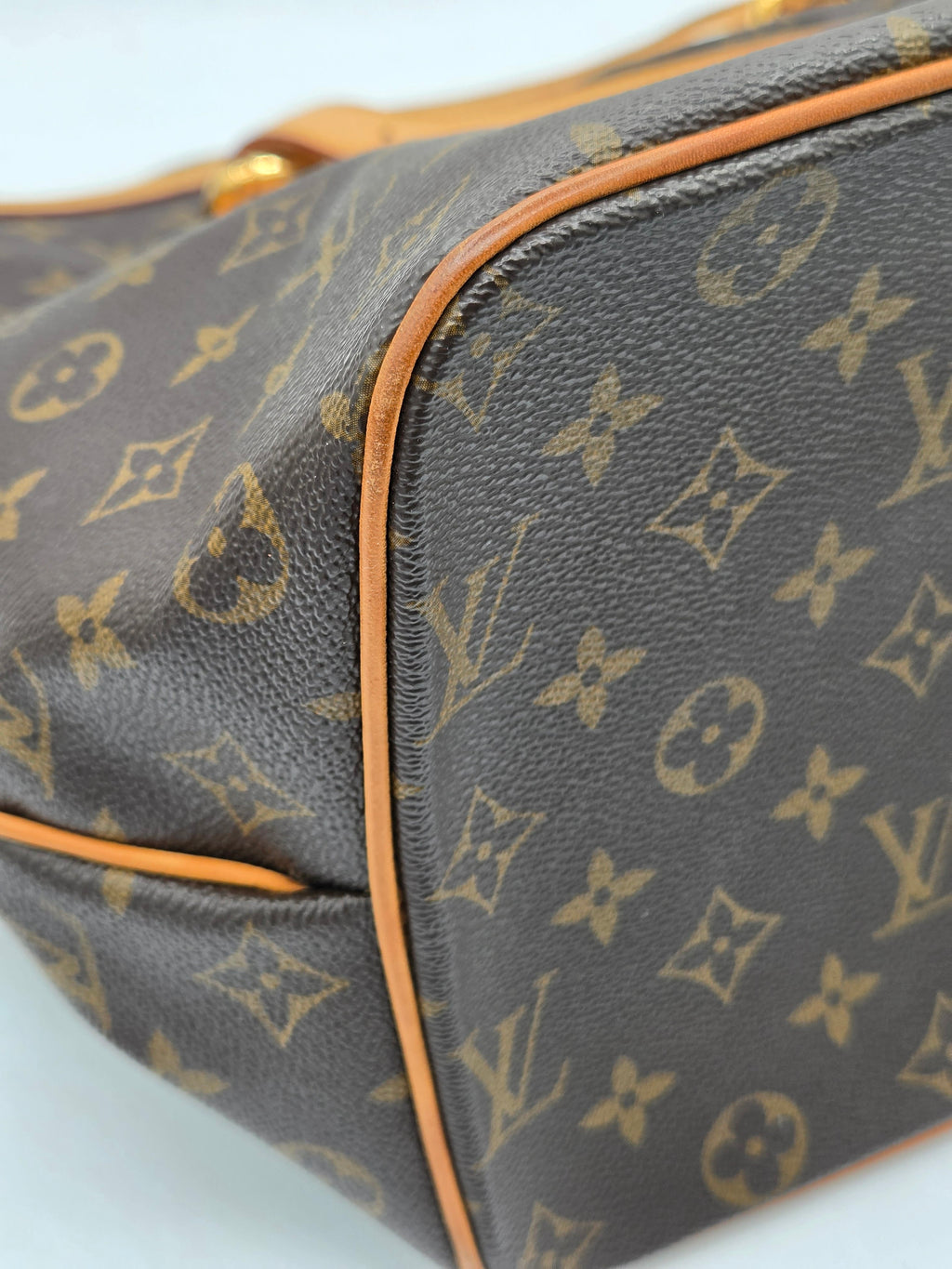 Close-up of a Louis Vuitton monogram bag with brown leather trim.