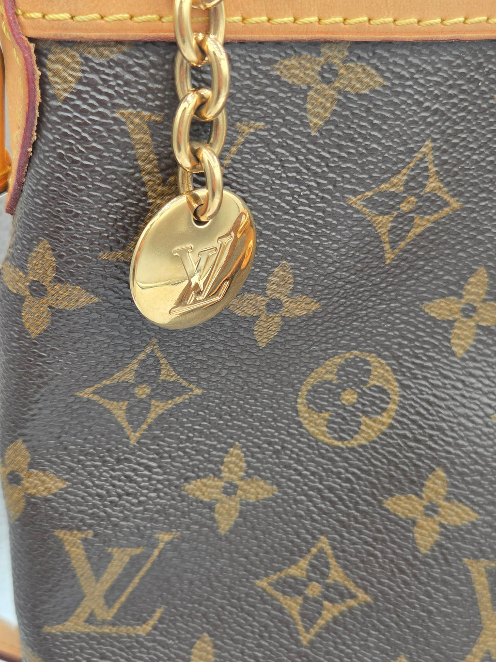 Close-up of a Louis Vuitton handbag with monogram pattern and gold chain.