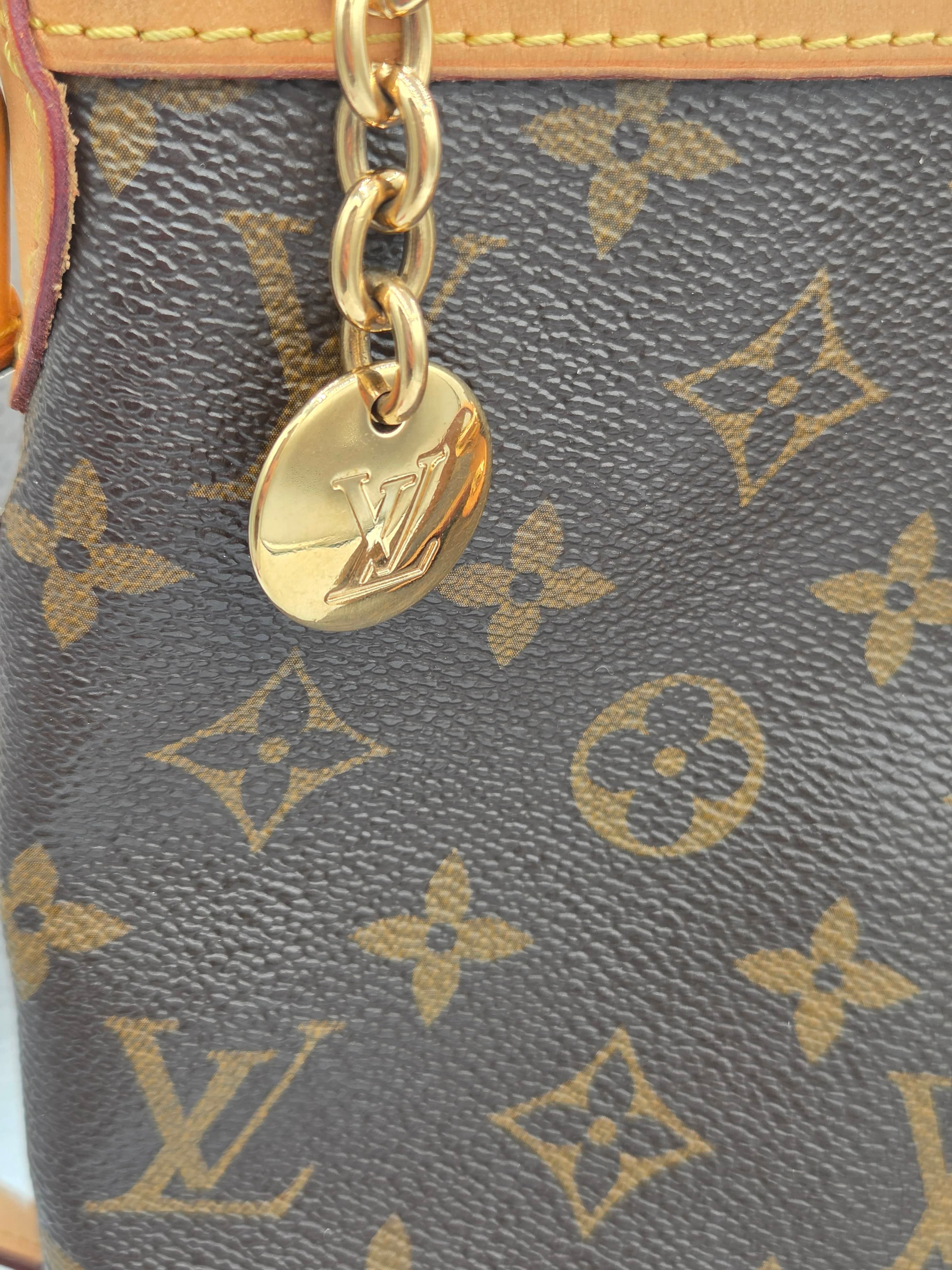 Close-up of a Louis Vuitton handbag with monogram pattern and gold chain.
