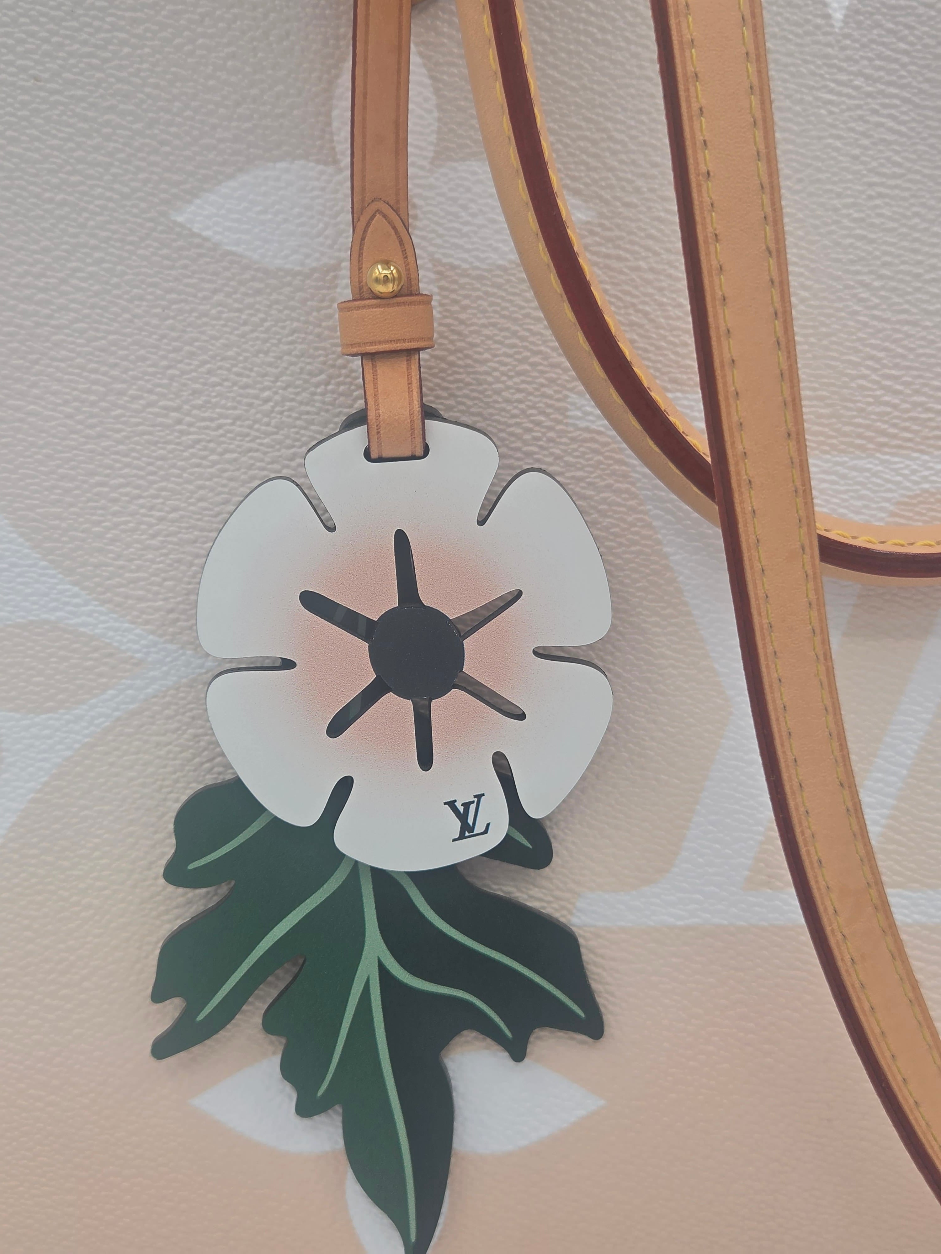 Floral-shaped bag charm with a brand logo on a beige background