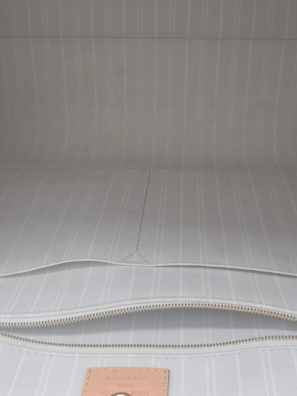 Close-up of a light gray textured surface with a zipper and brown label.
