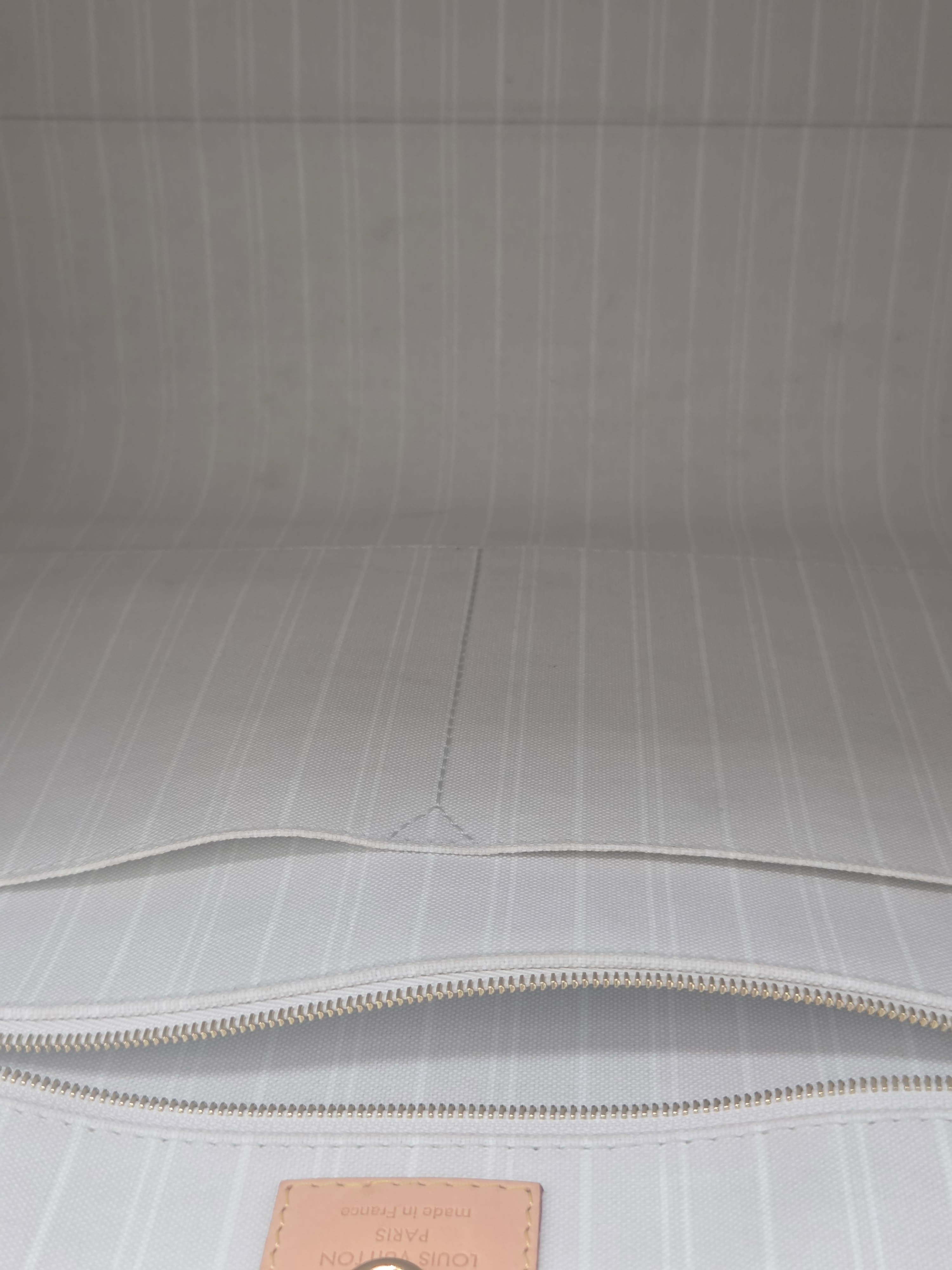 Close-up of a light gray textured surface with a zipper and brown label.