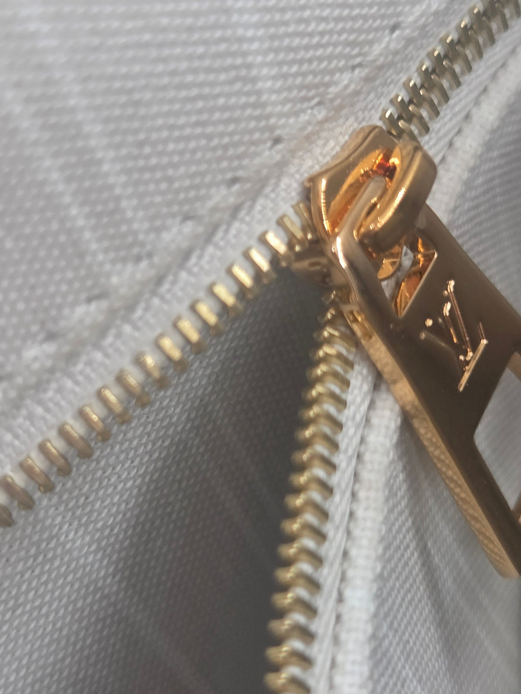 Close-up of a gold zipper on a white fabric background