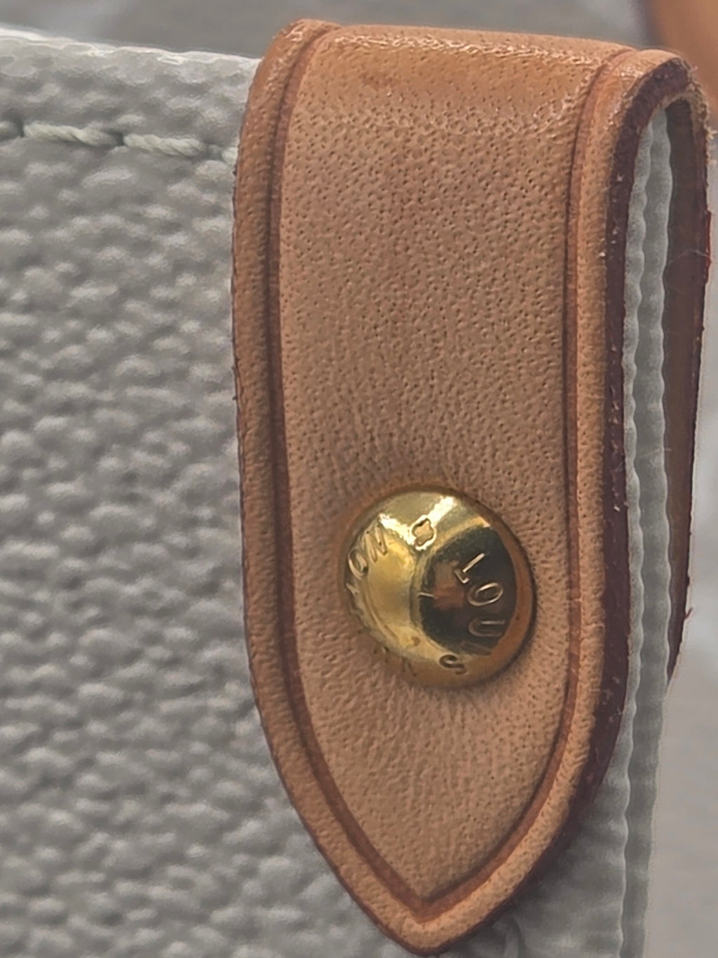 Brown leather strap with a gold button on a textured surface