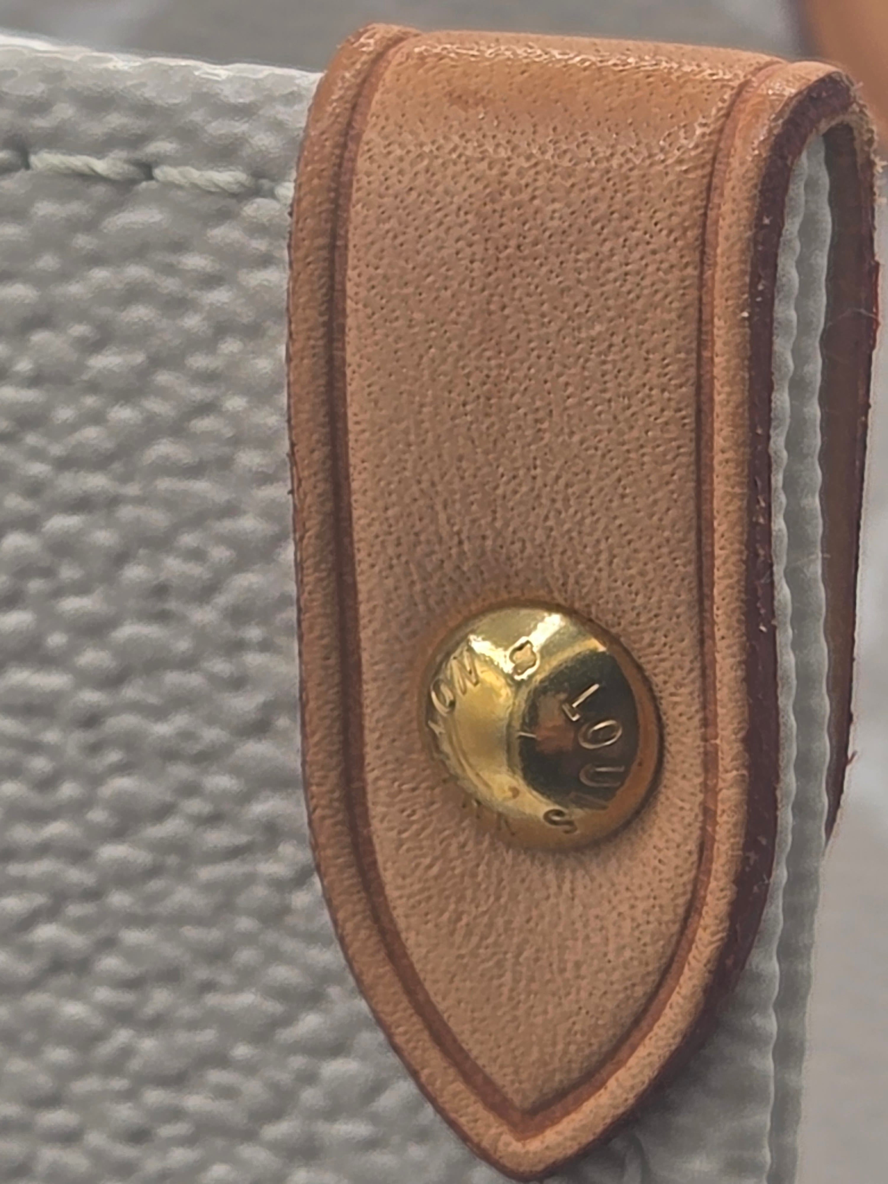 Brown leather strap with a gold button on a textured surface