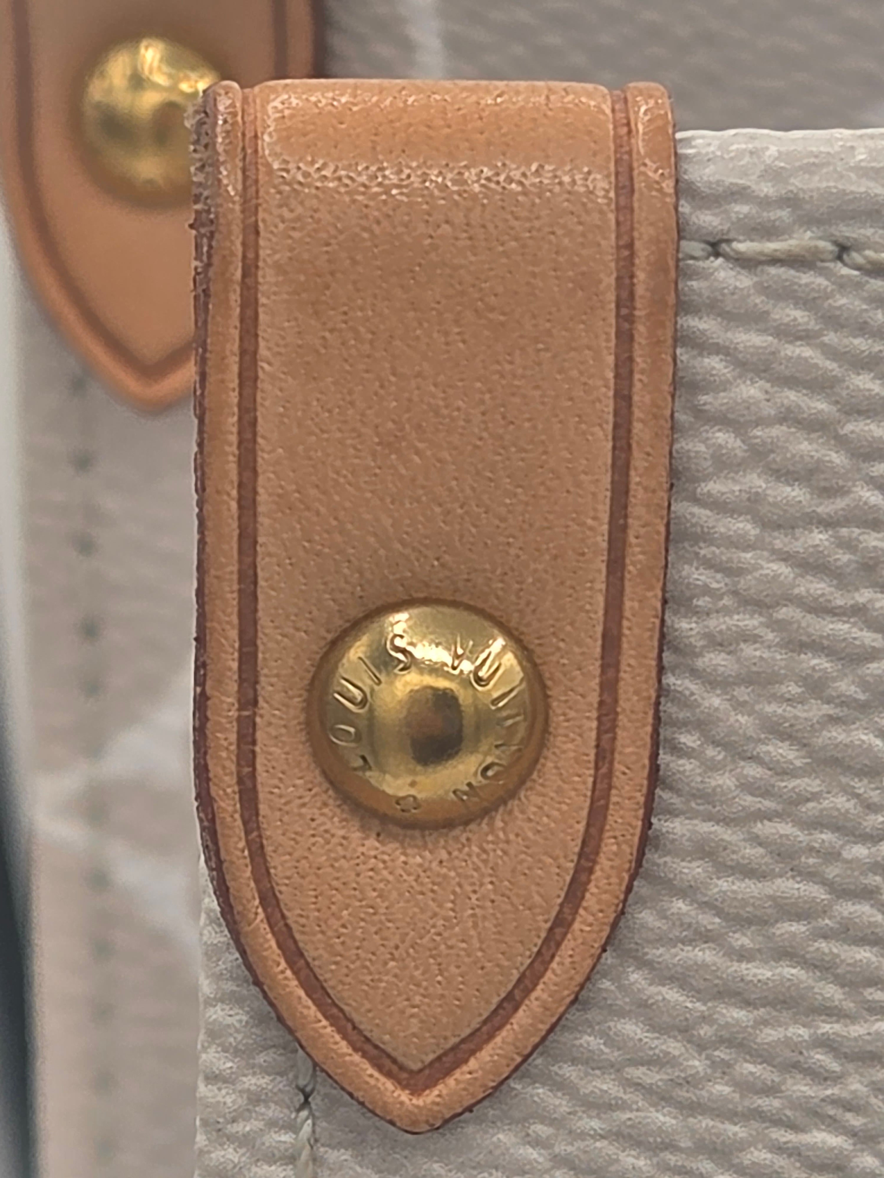 Close-up of a leather strap with a gold buckle on a textured surface