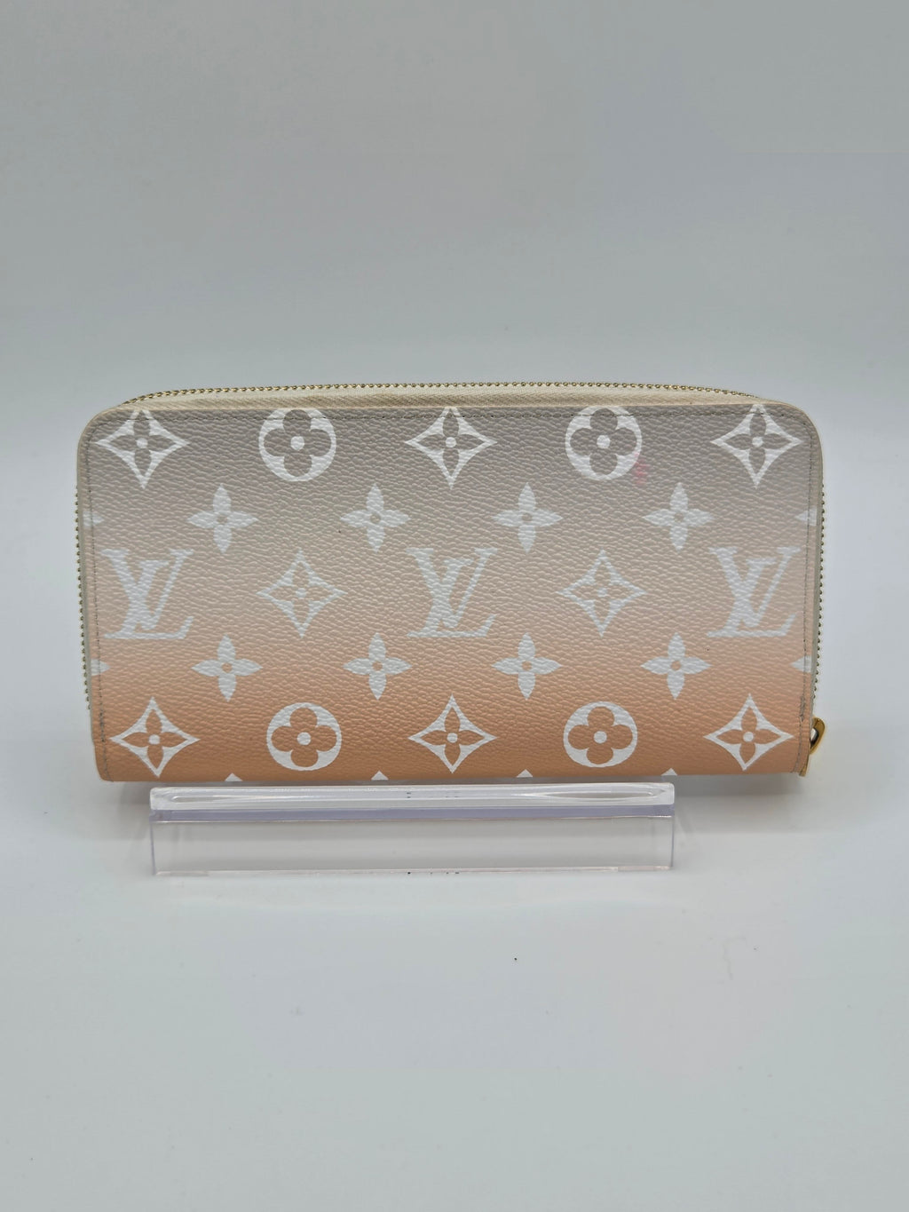 Designer wallet with monogram pattern on a light gray background