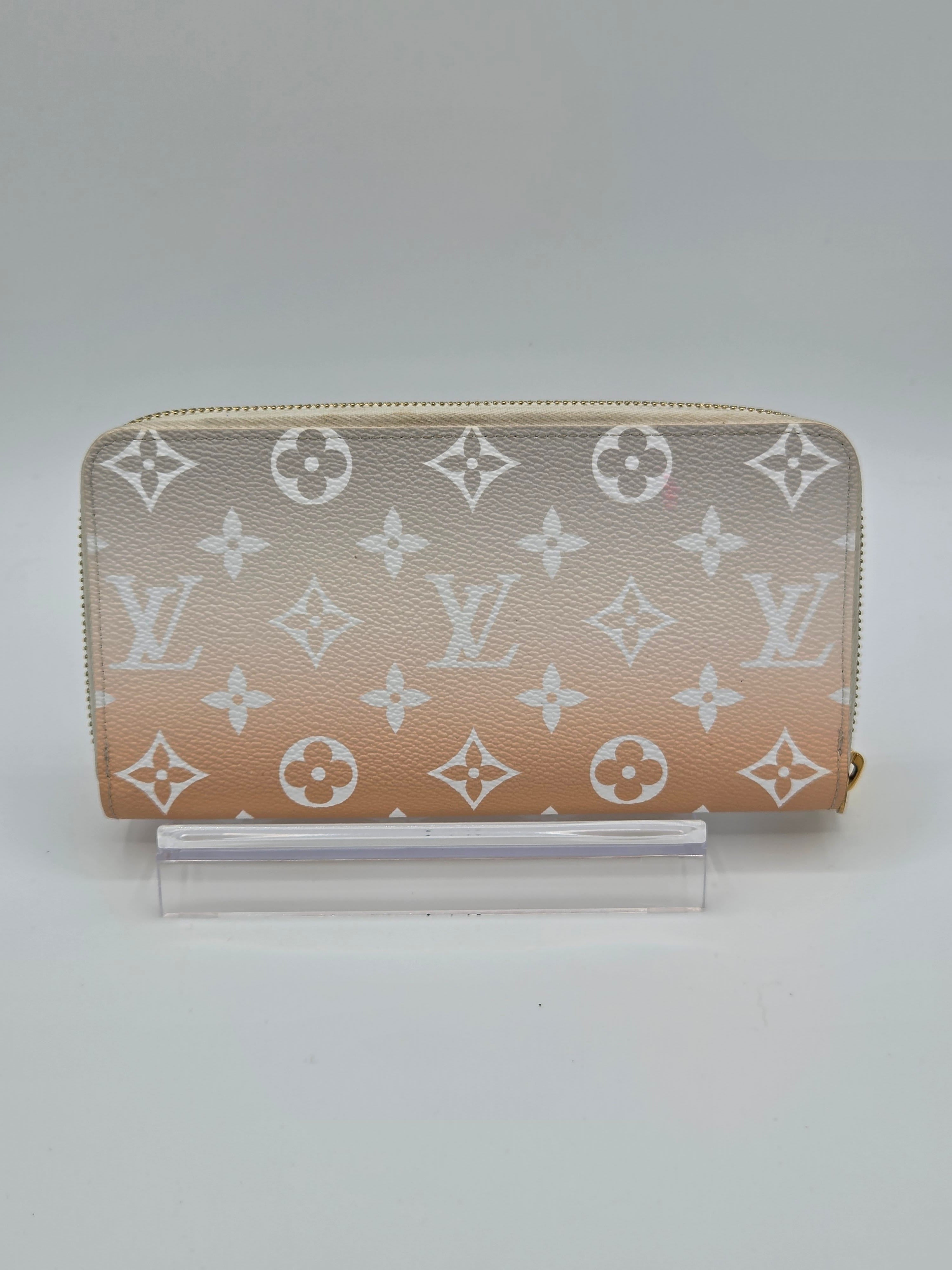 Designer wallet with monogram pattern on a light gray background