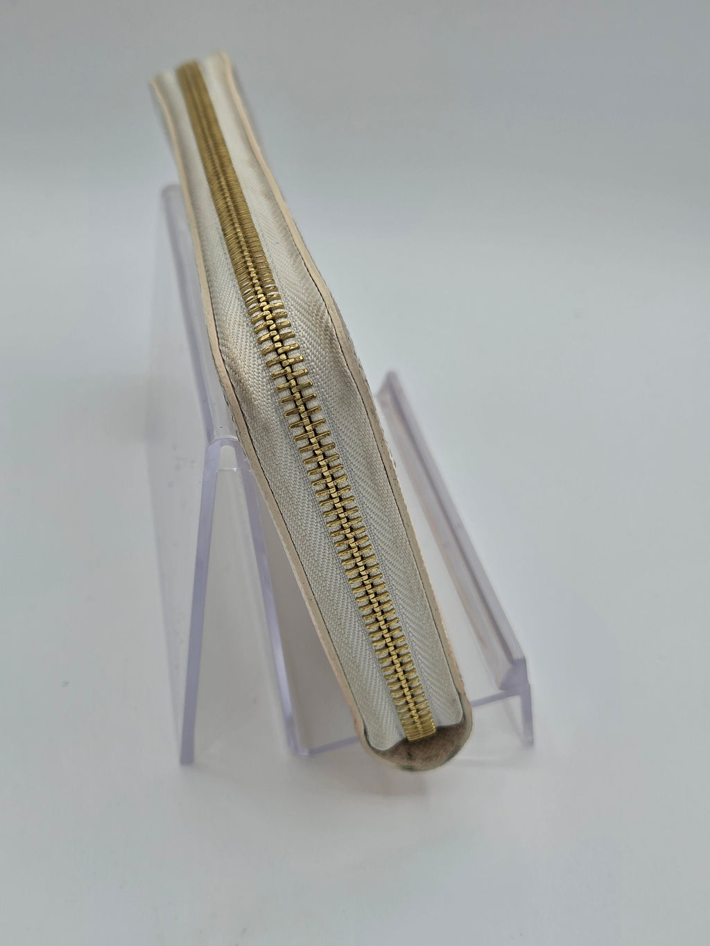 Beige zipper on a clear stand against a white background