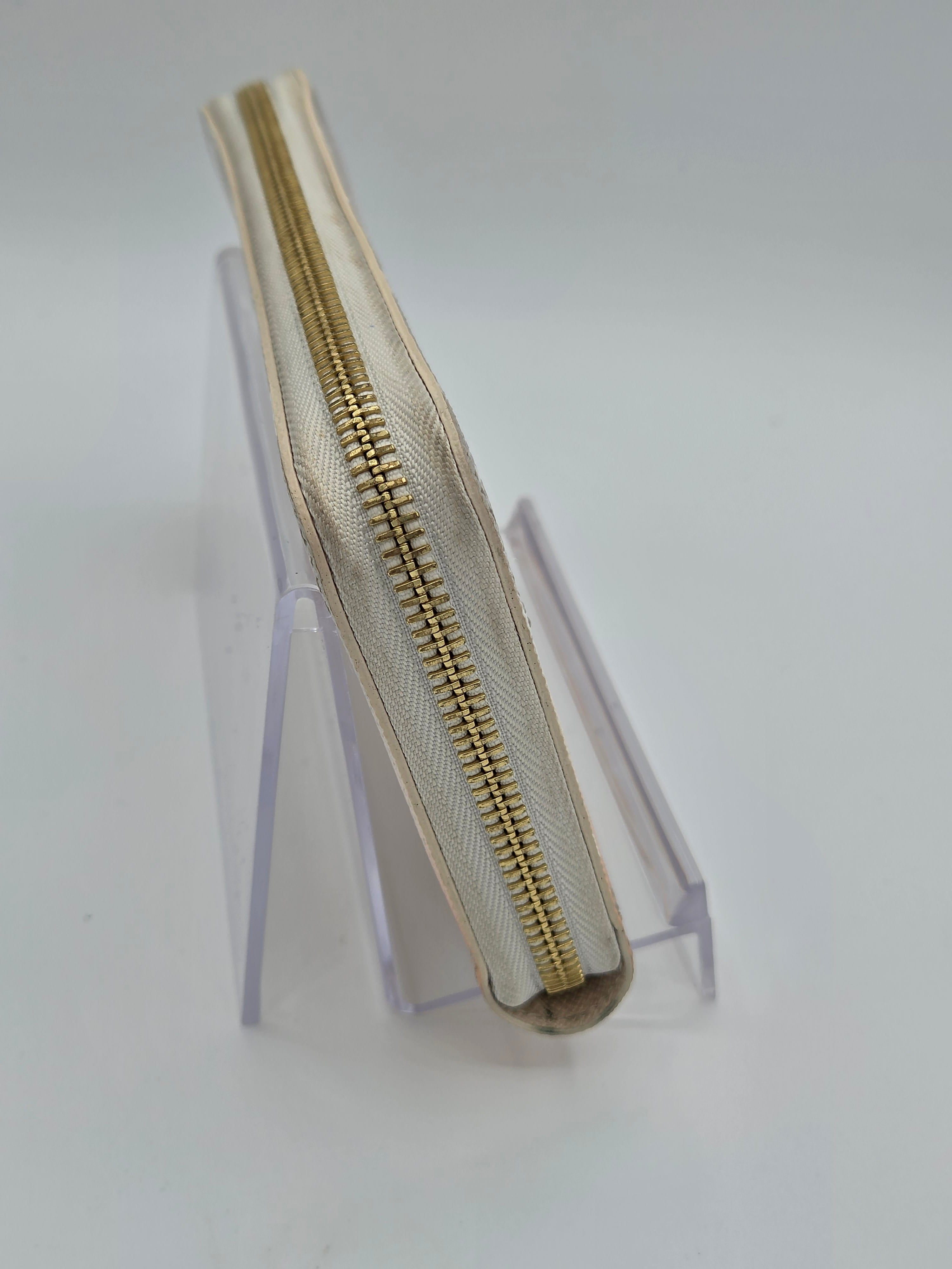 Beige zipper on a clear stand against a white background