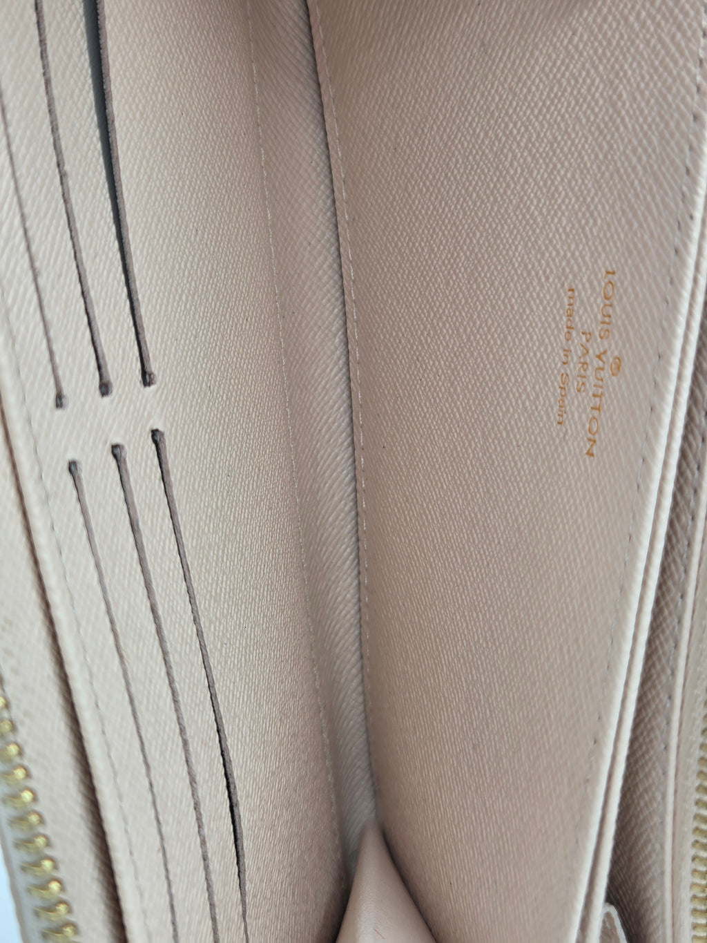 Close-up of a beige Louis Vuitton wallet with visible branding.