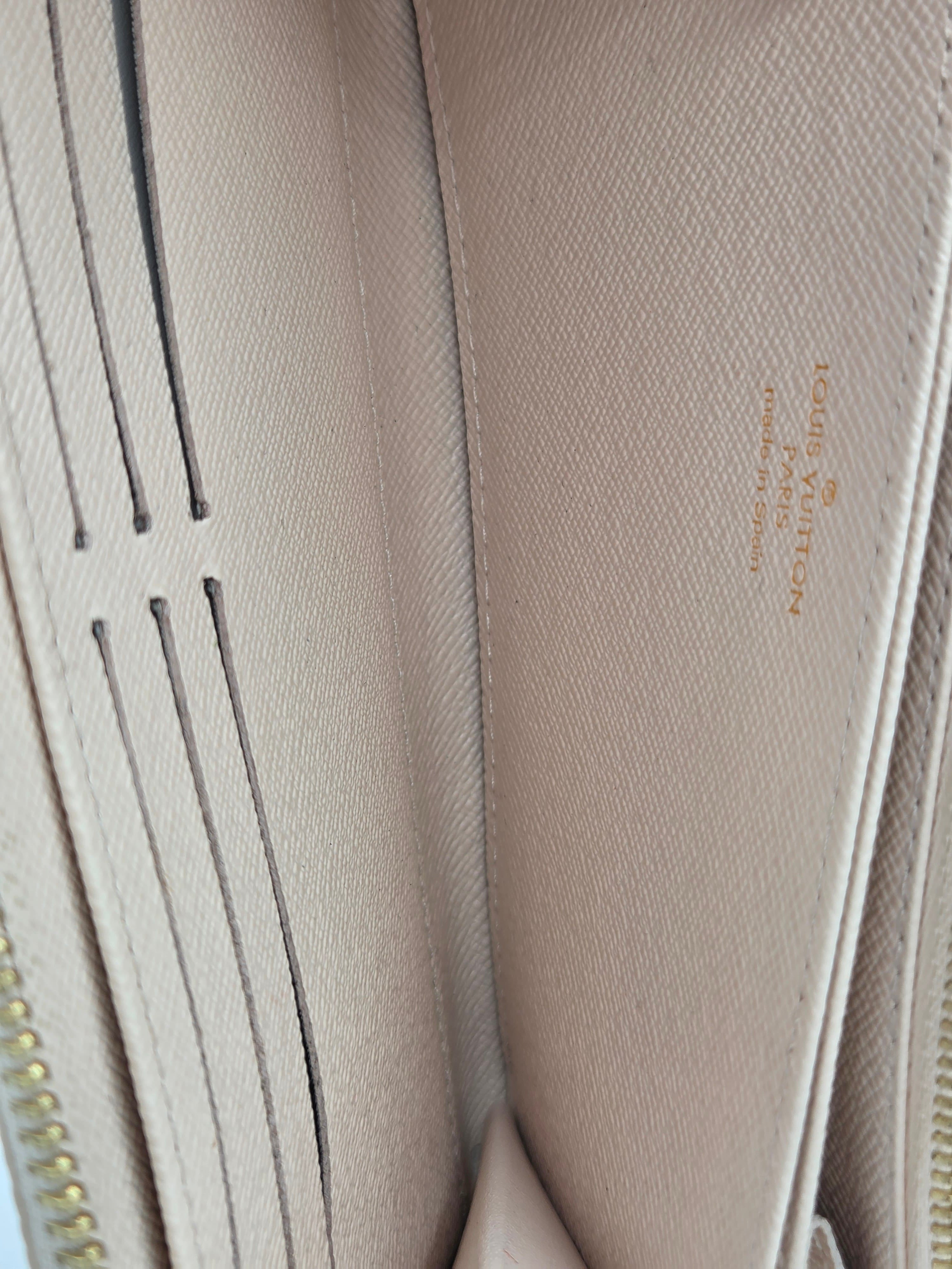 Close-up of a beige Louis Vuitton wallet with visible branding.