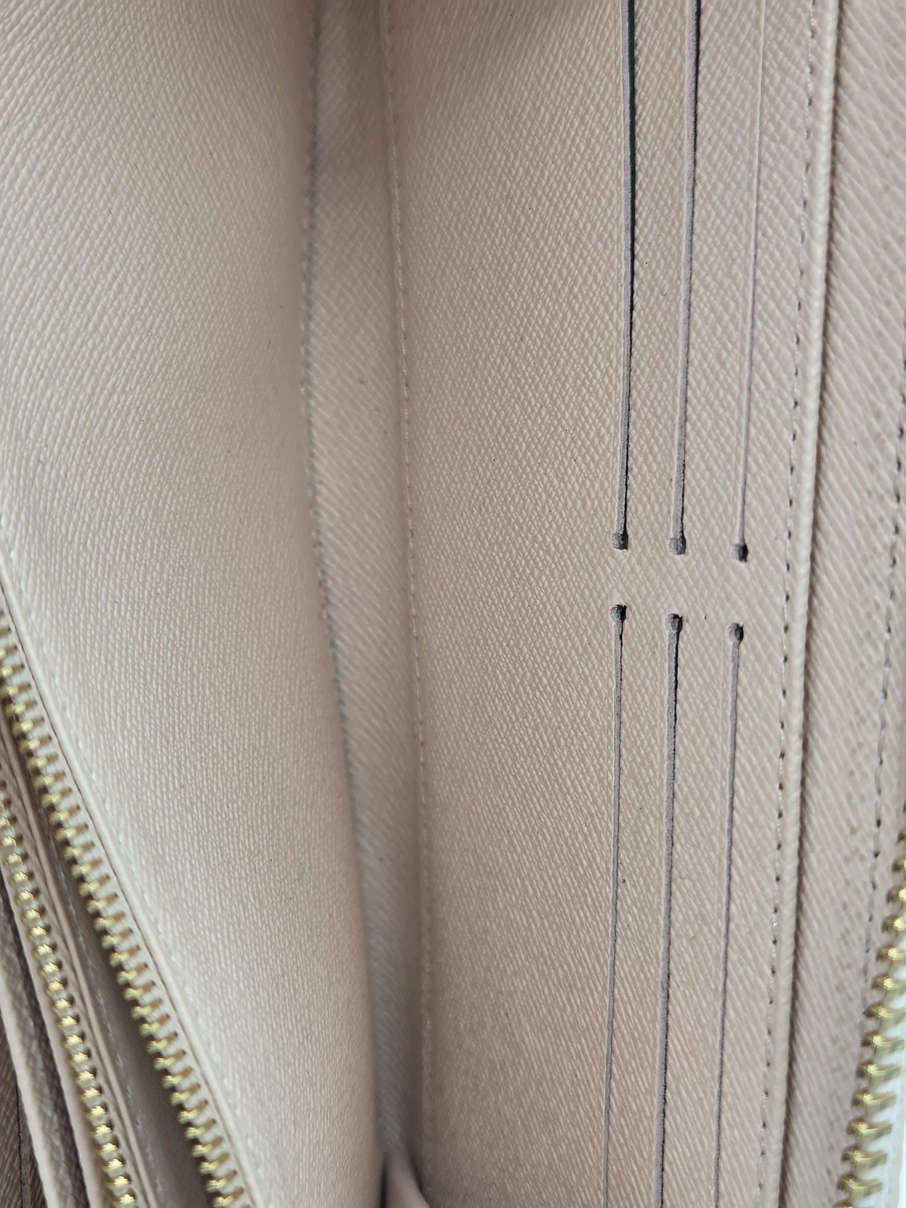 Close-up of a beige leather wallet with gold zipper