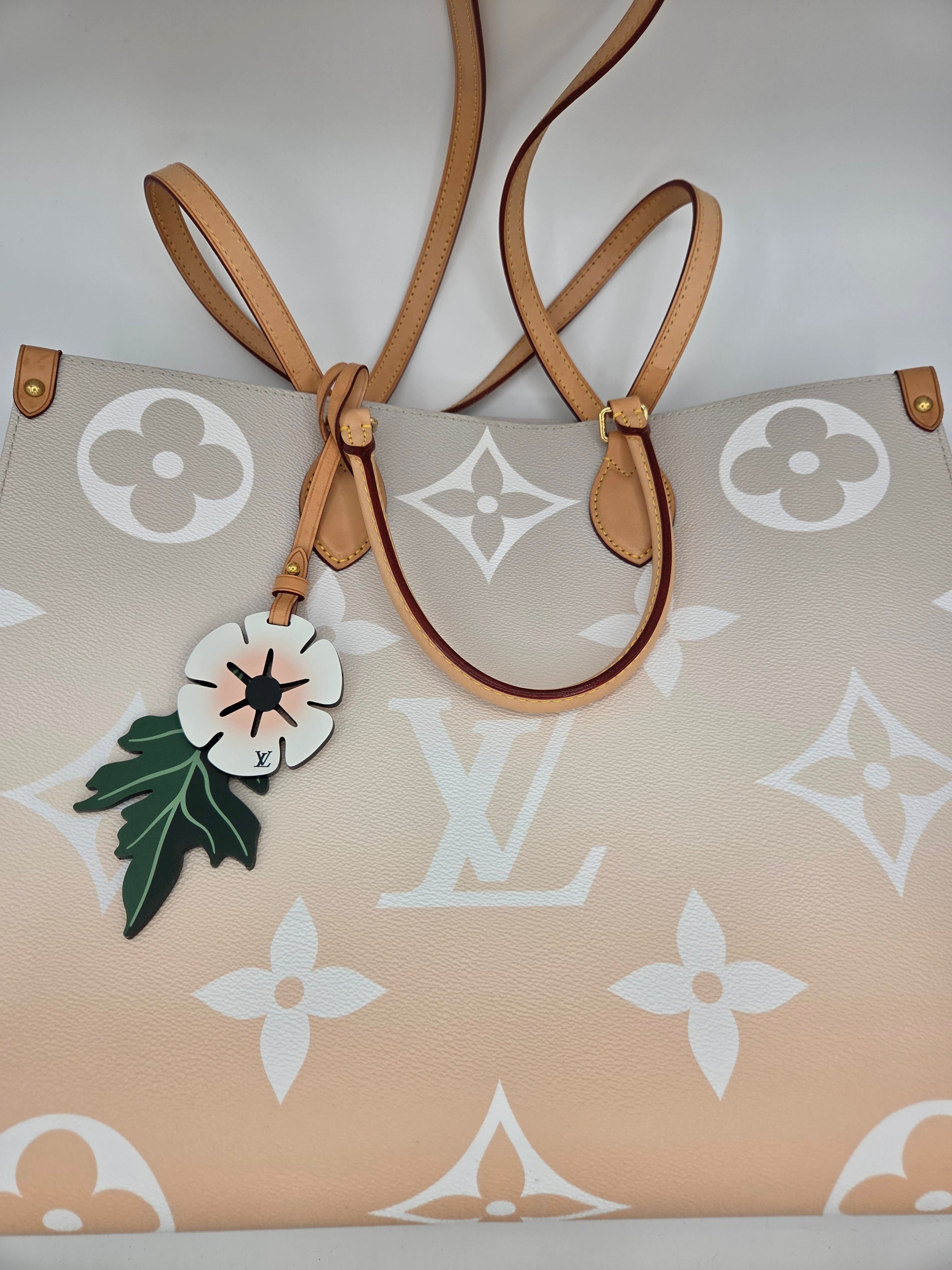 Beige handbag with floral design and strap on a light background