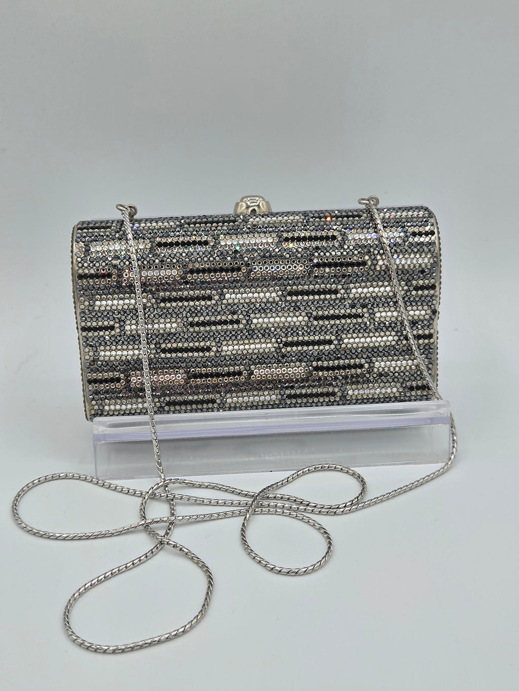 Silver beaded clutch bag with a chain strap on a light gray background