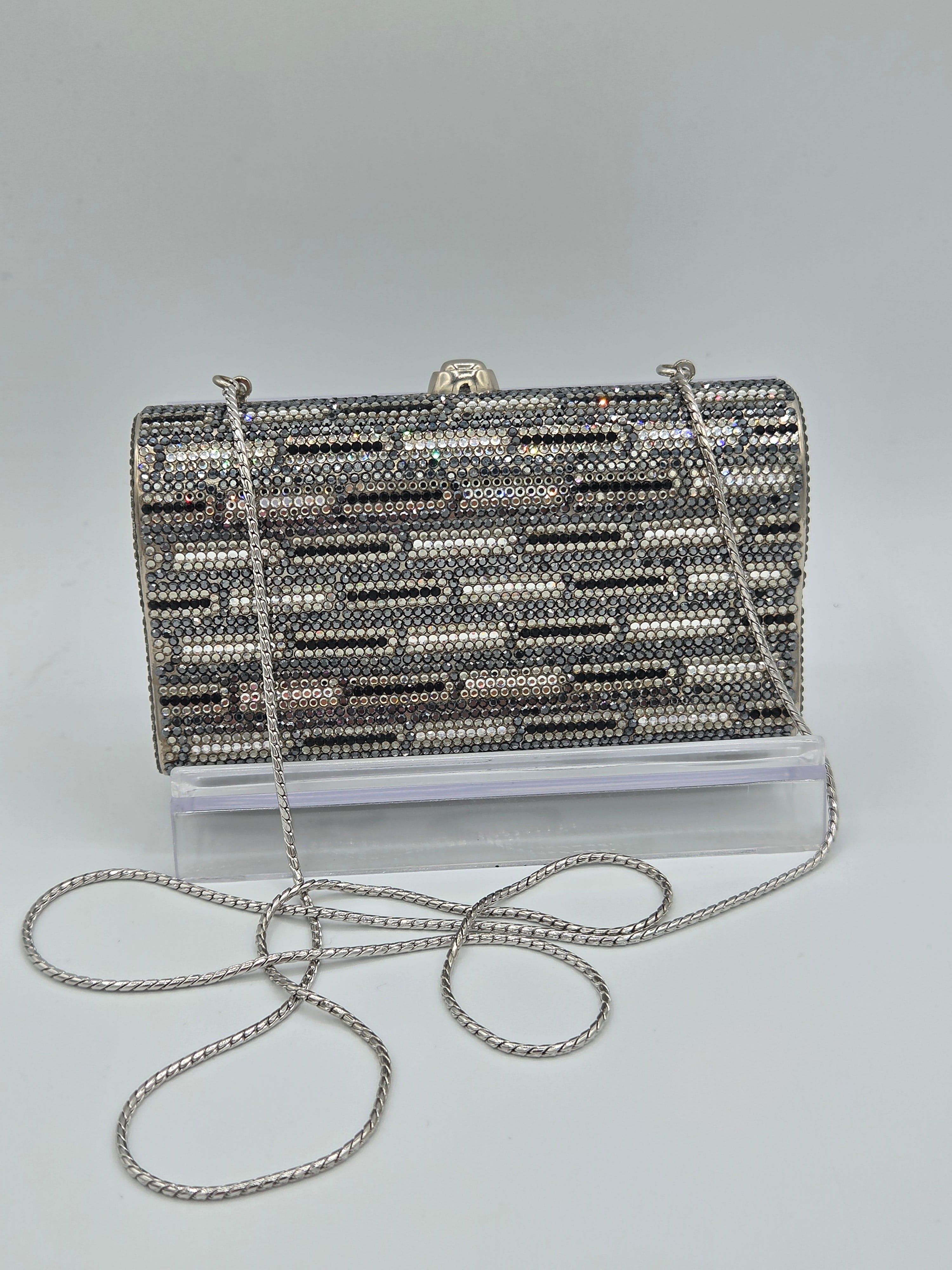 Silver beaded clutch bag with a chain strap on a light gray background
