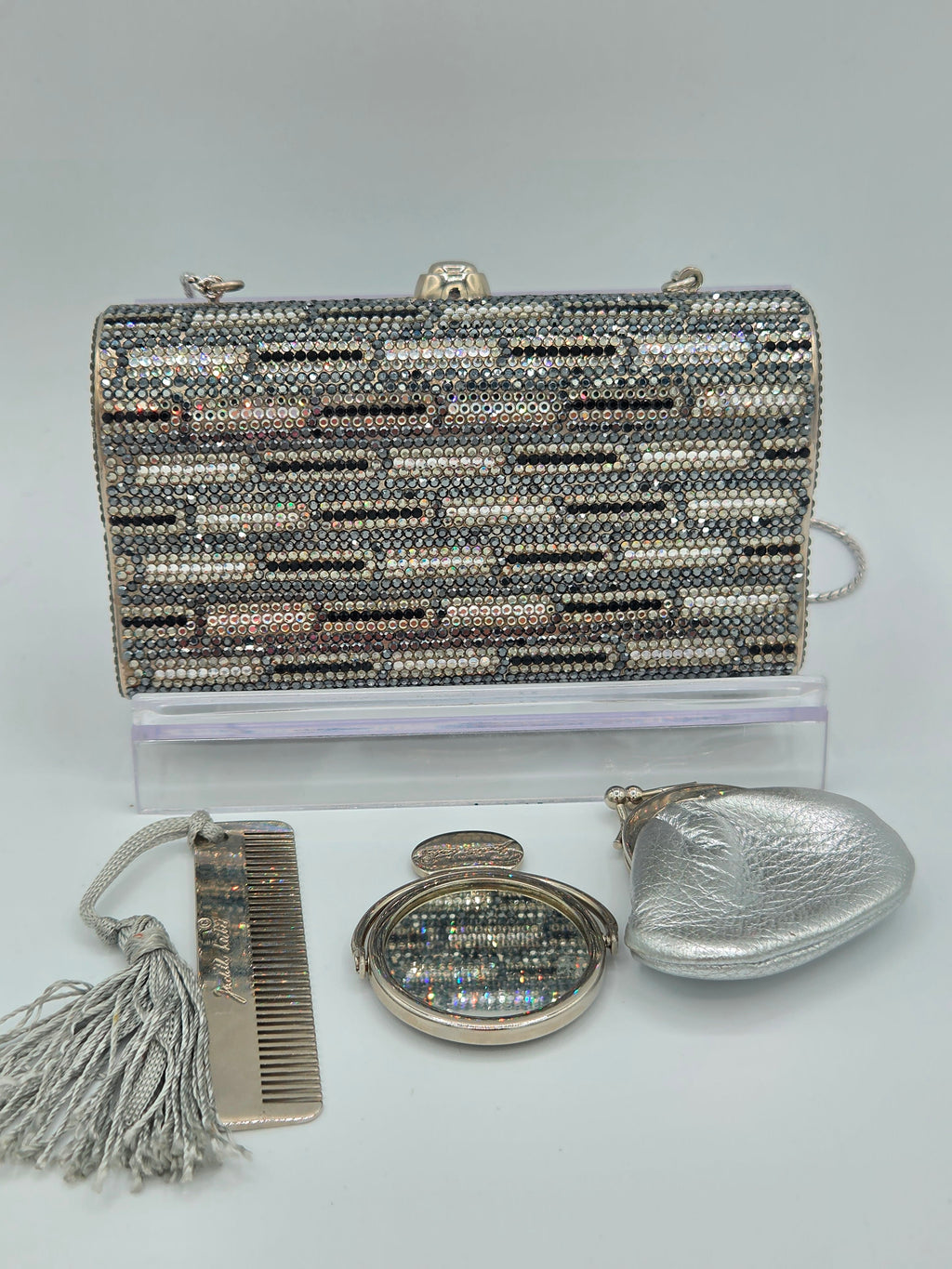Silver beaded handbag with matching compact mirror and comb on a light gray background
