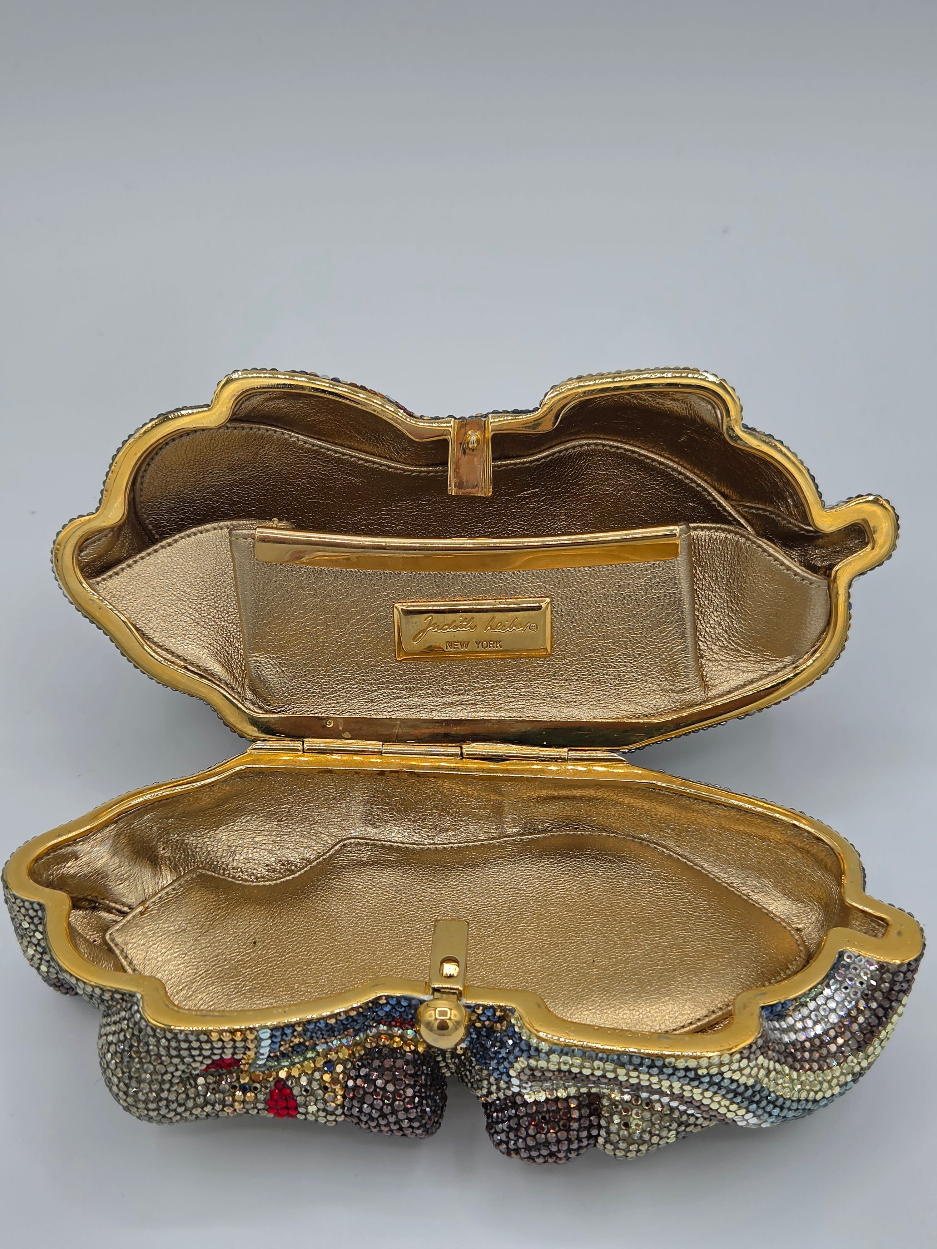 Gold clutch bag with intricate detailing on a gray background