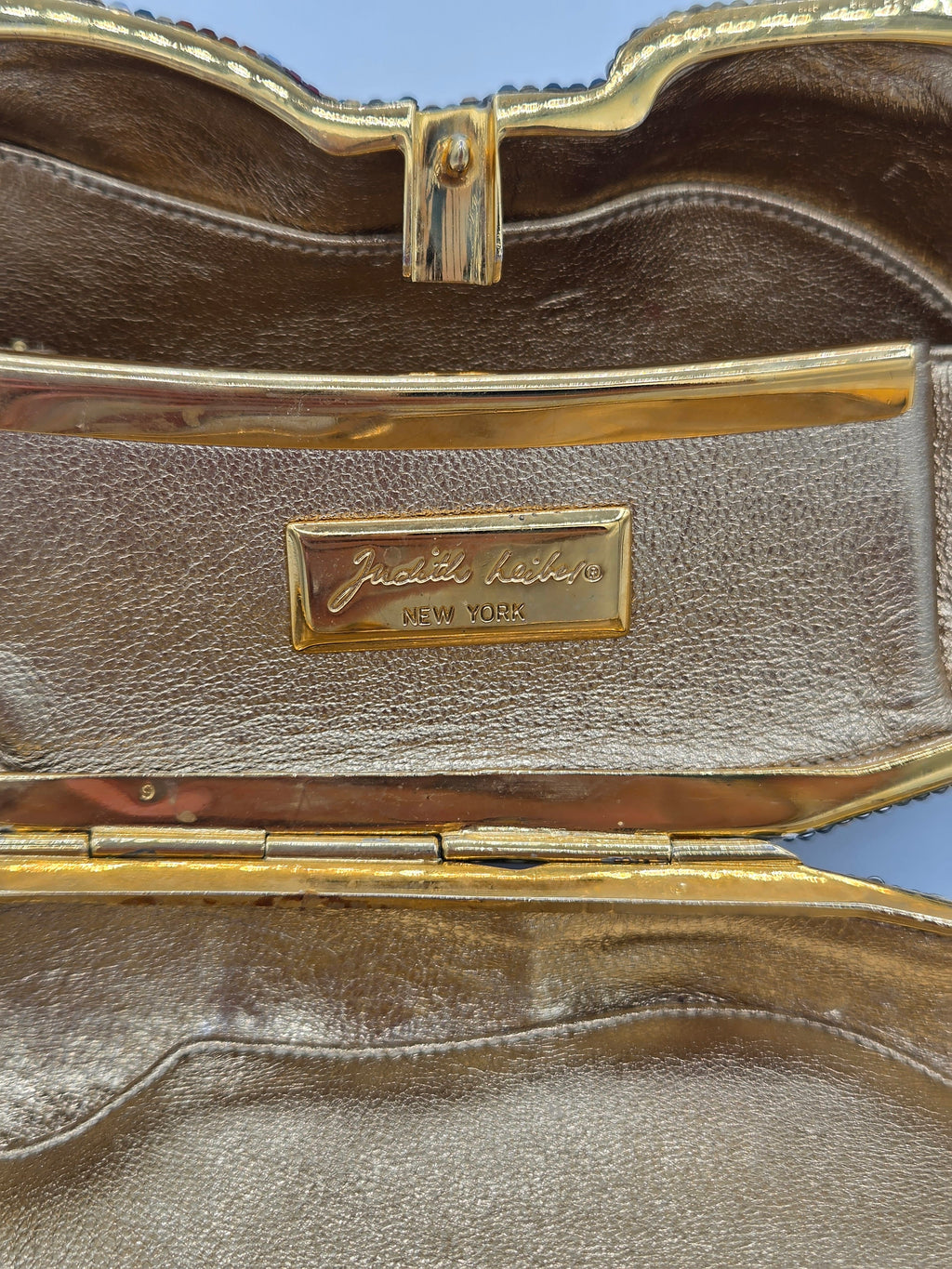 Brown leather case with gold trim and a visible brand logo on a blue background