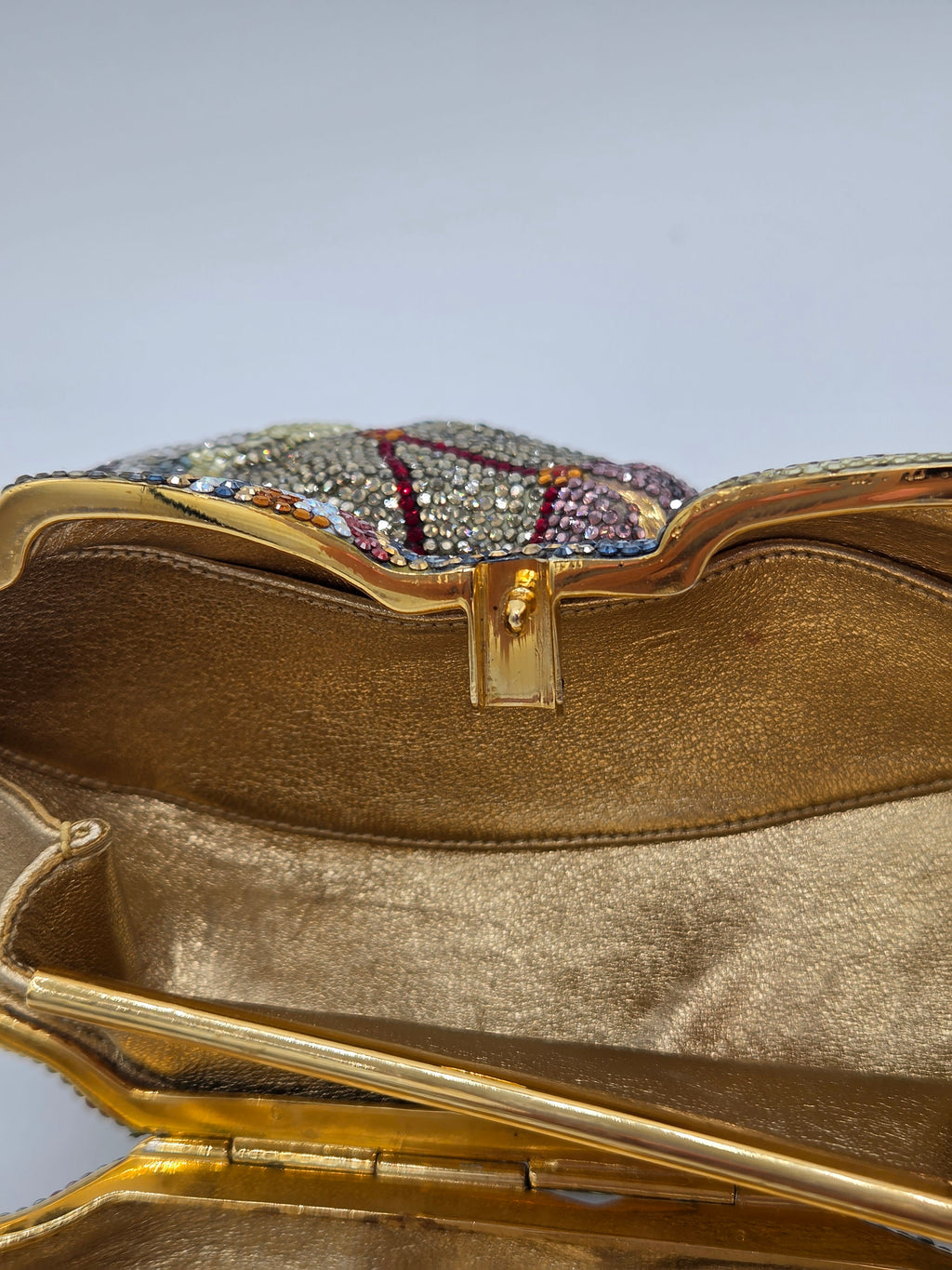 Gold clutch with intricate design on a light gray background