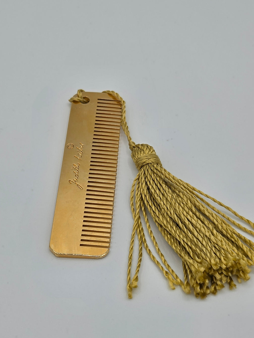 Gold comb with tassel on a light gray background