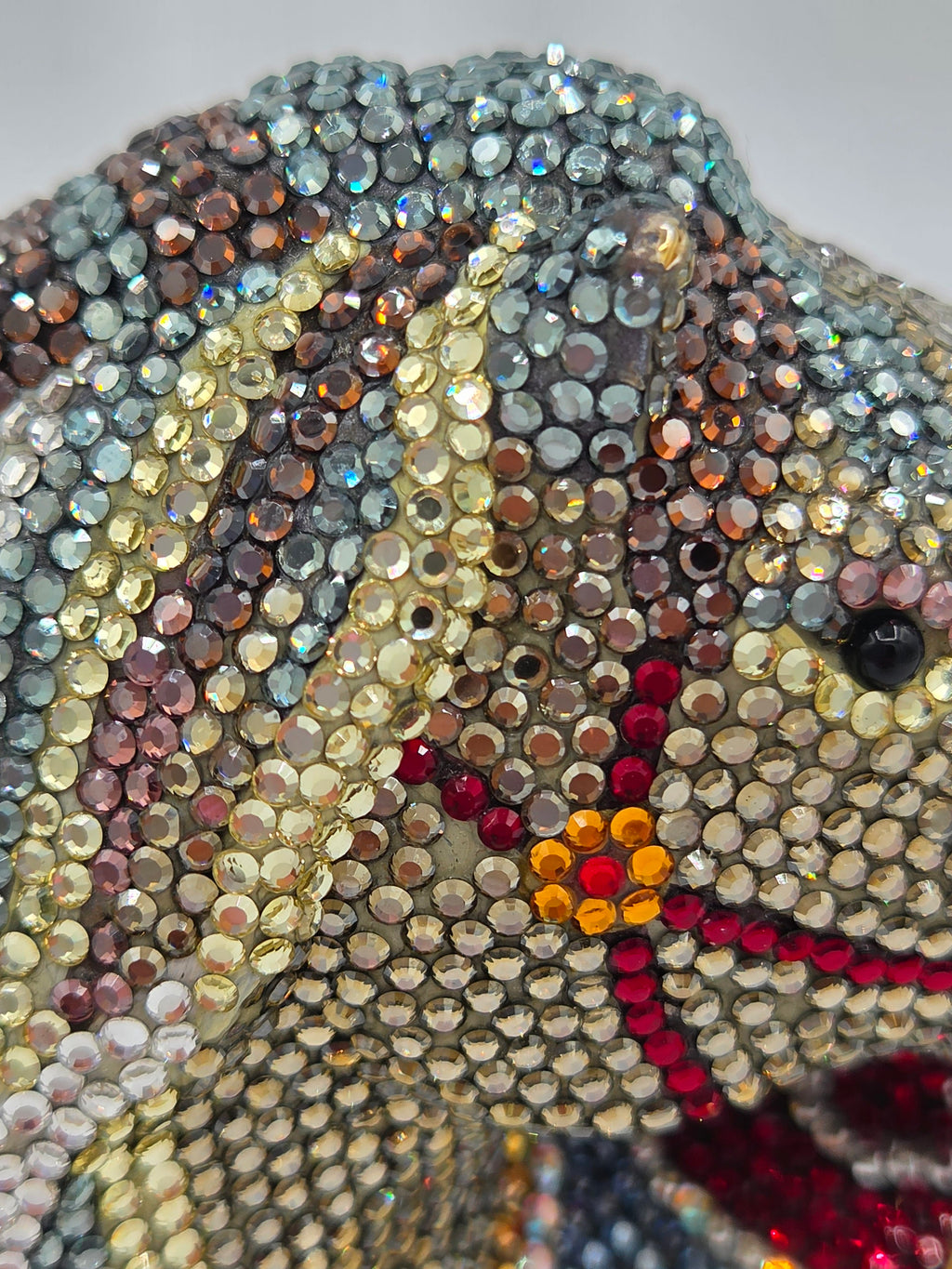 Close-up of a decorative item with multicolored gemstones on a plain background