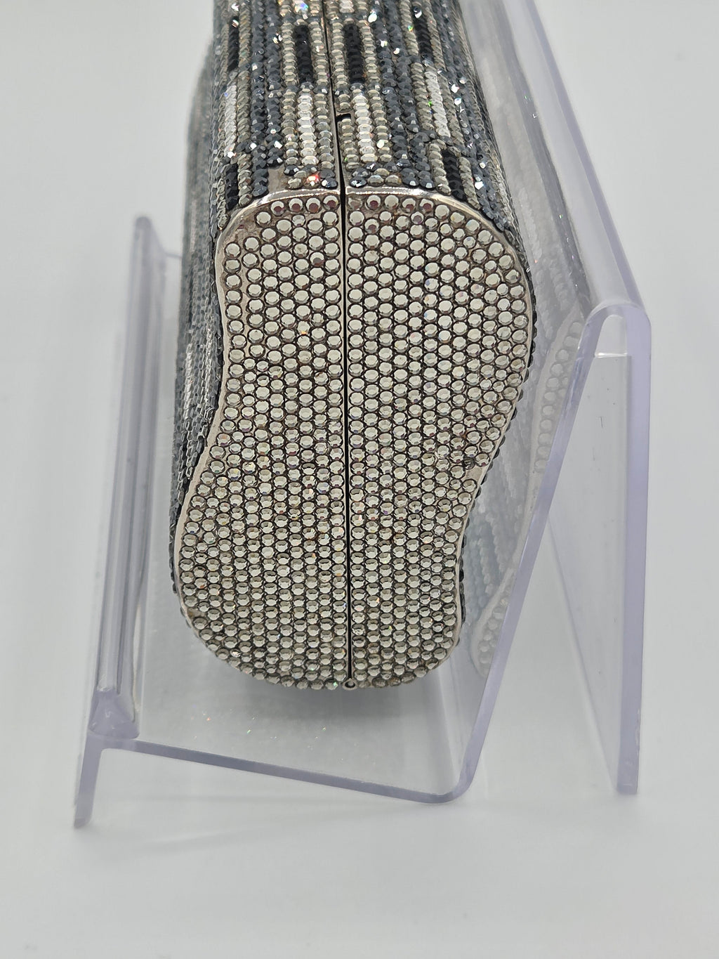 Silver beaded clutch on a clear stand against a white background