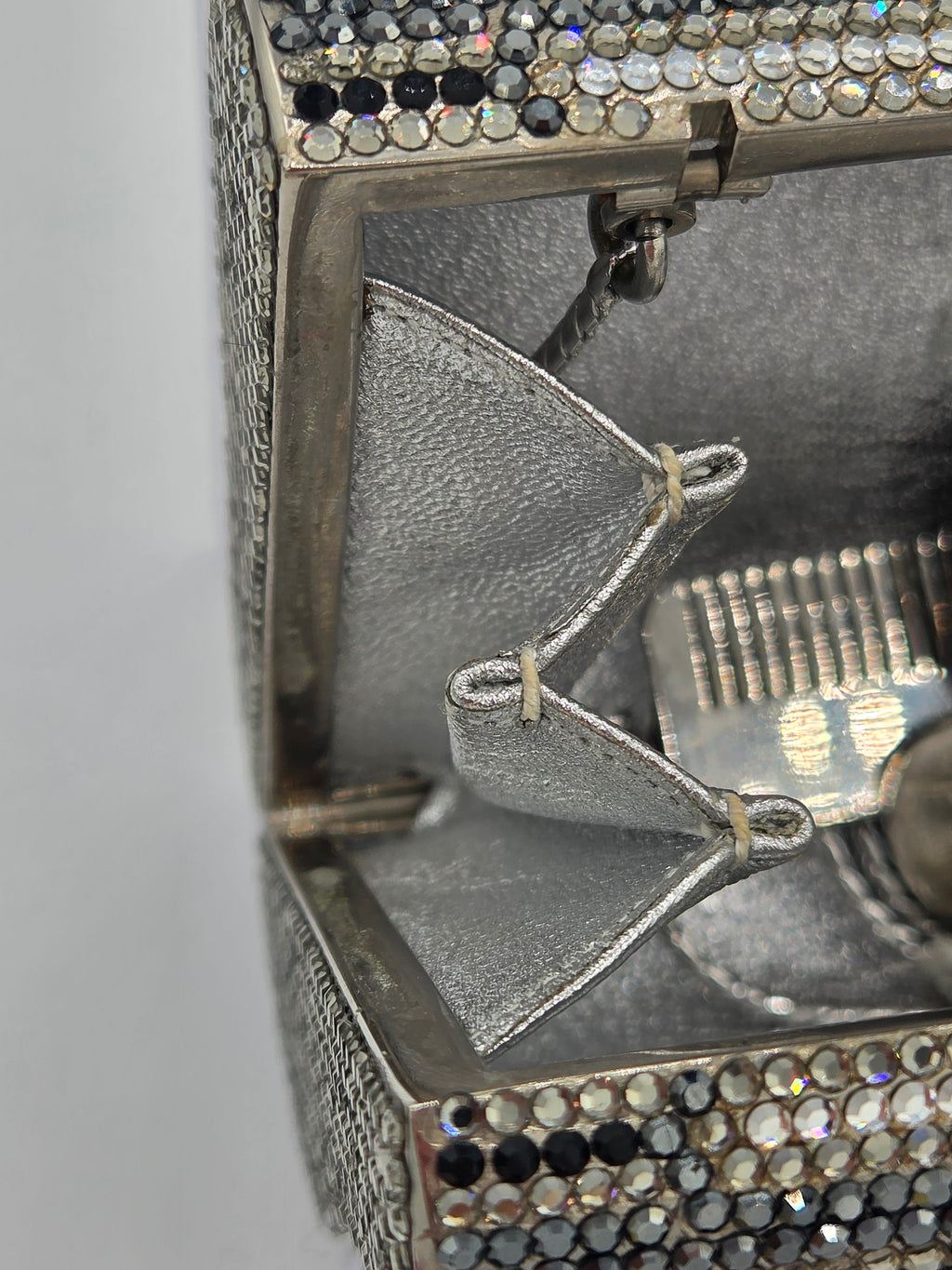 Close-up of a decorative object with intricate details and rhinestones on a gray background