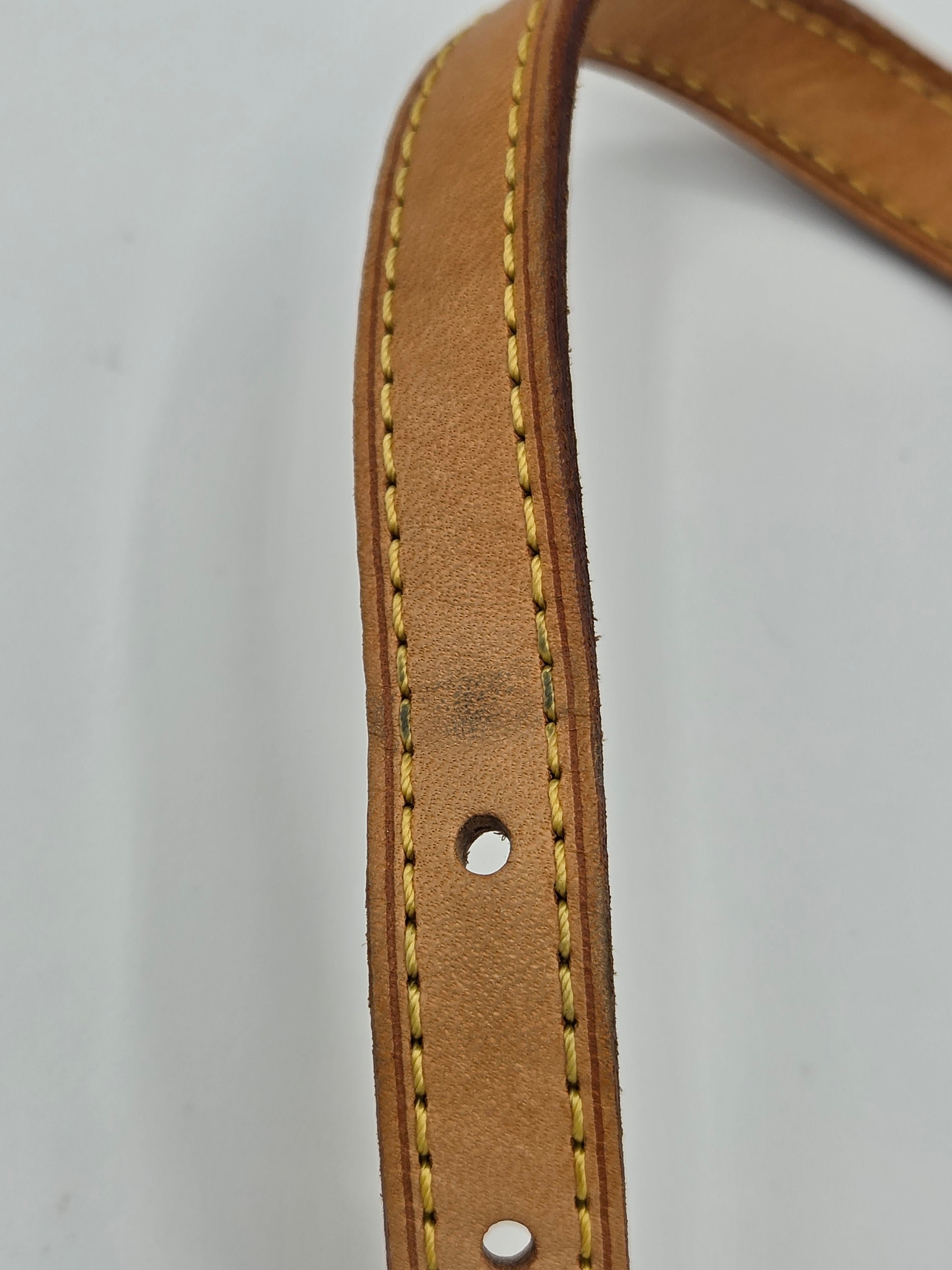 Close-up of a brown leather belt with visible stitching on a light gray background