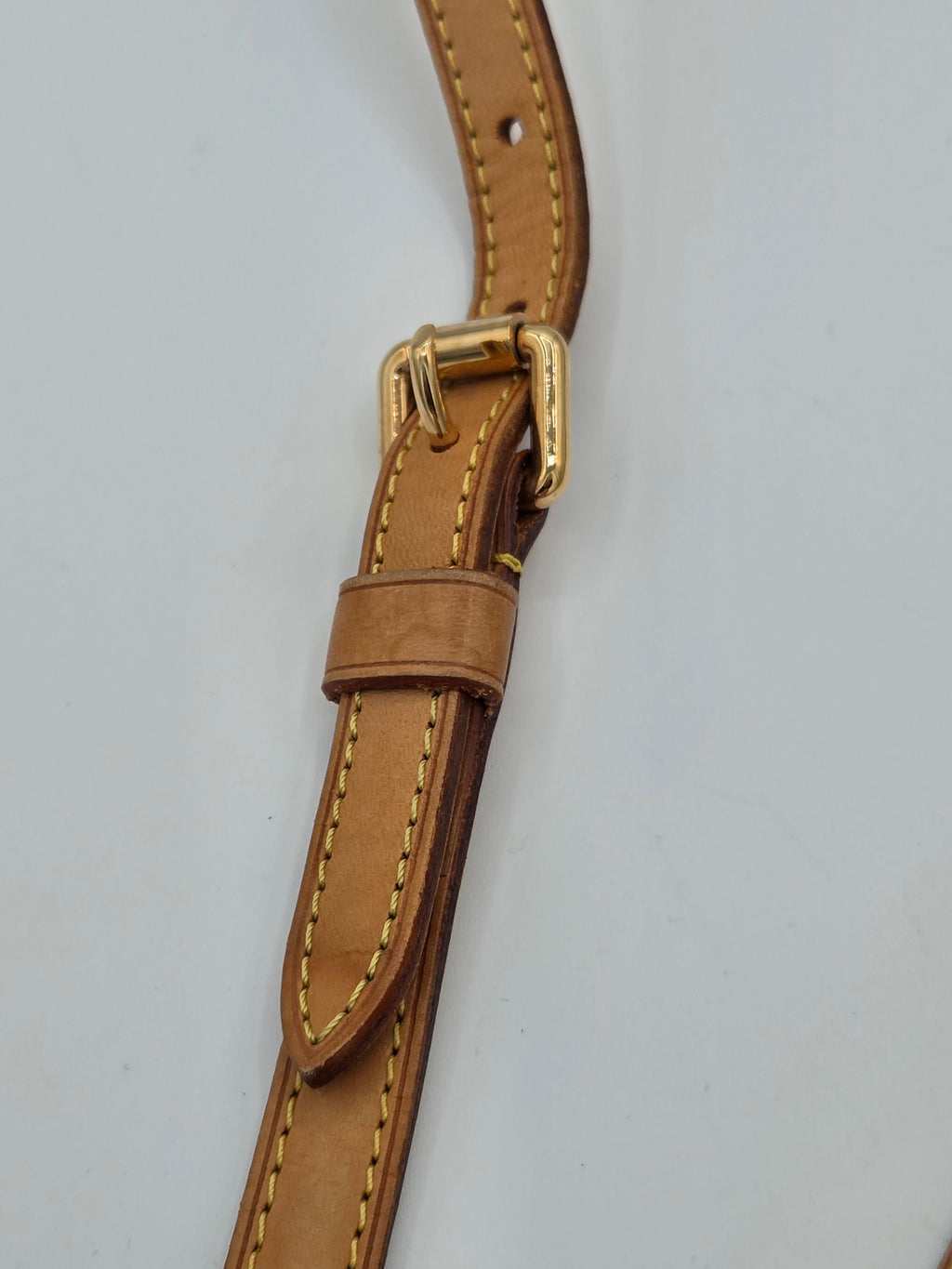 Brown leather belt with a gold buckle on a light gray background