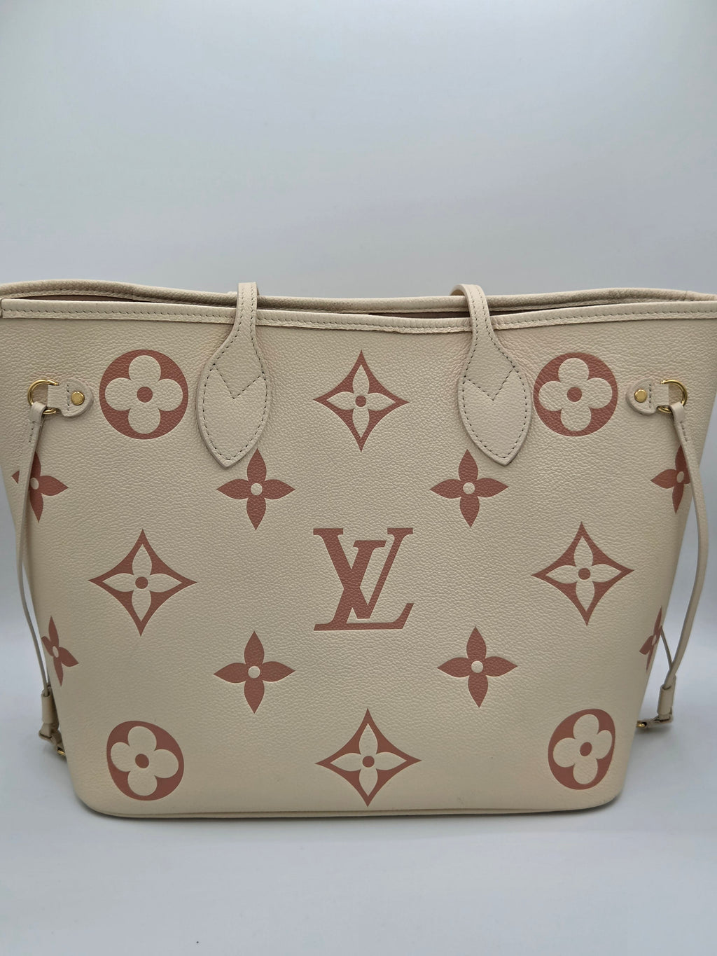 Beige handbag with brown floral and monogram pattern on a white background