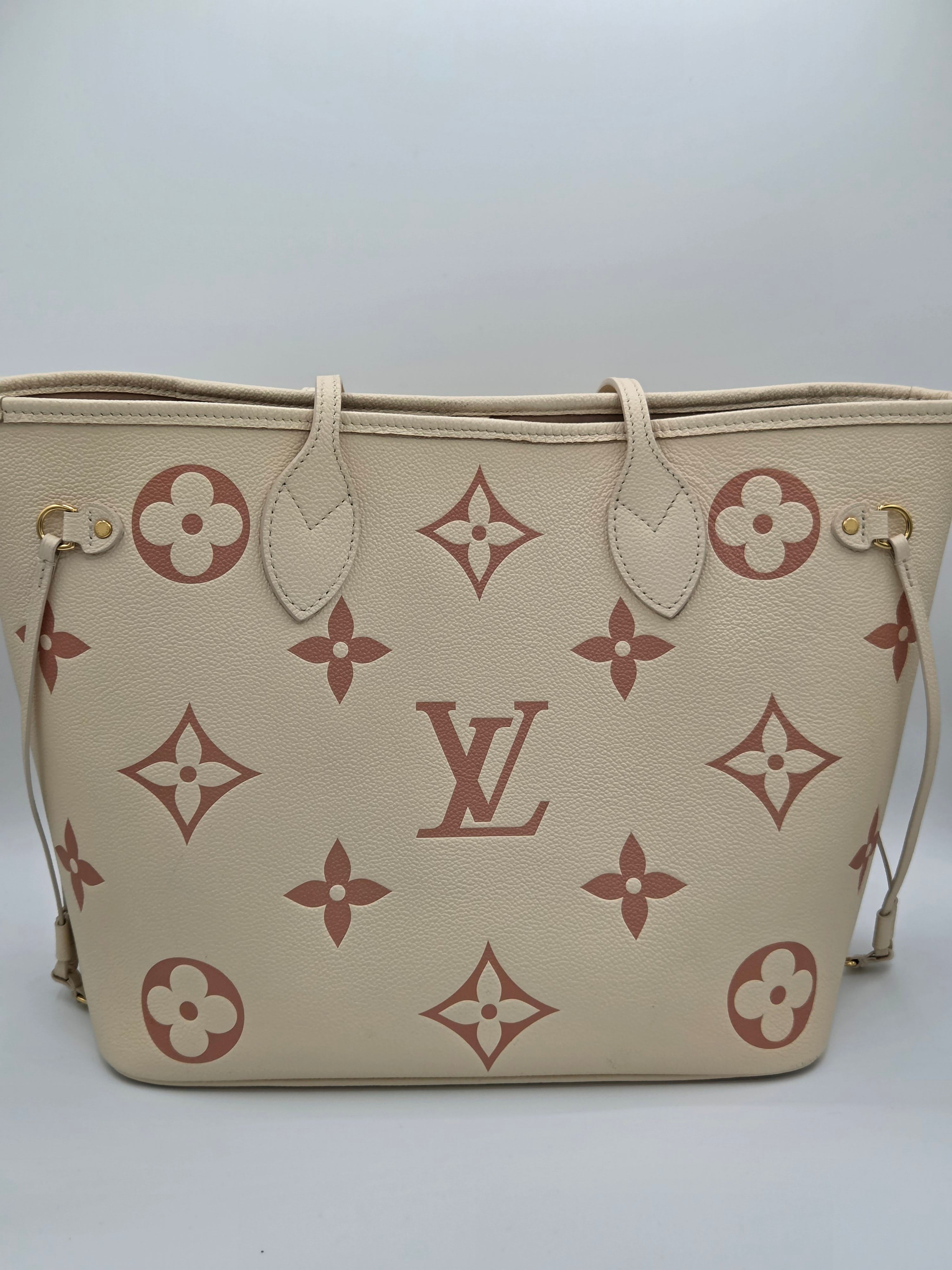 Beige handbag with brown floral and monogram pattern on a white background