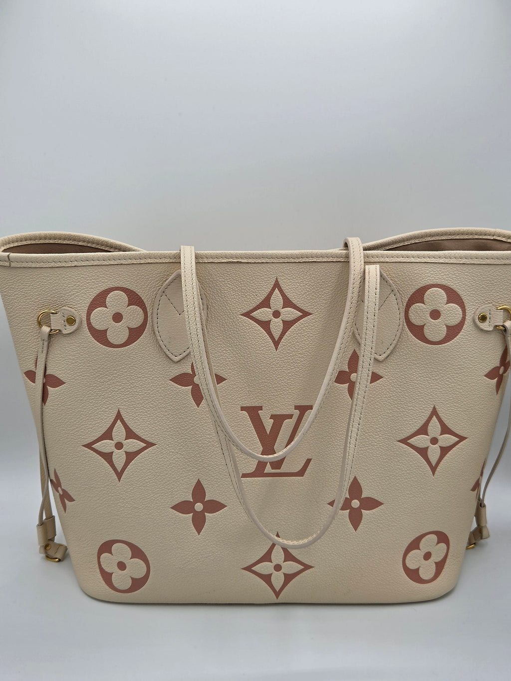 Beige handbag with brown monogram pattern on a white background
