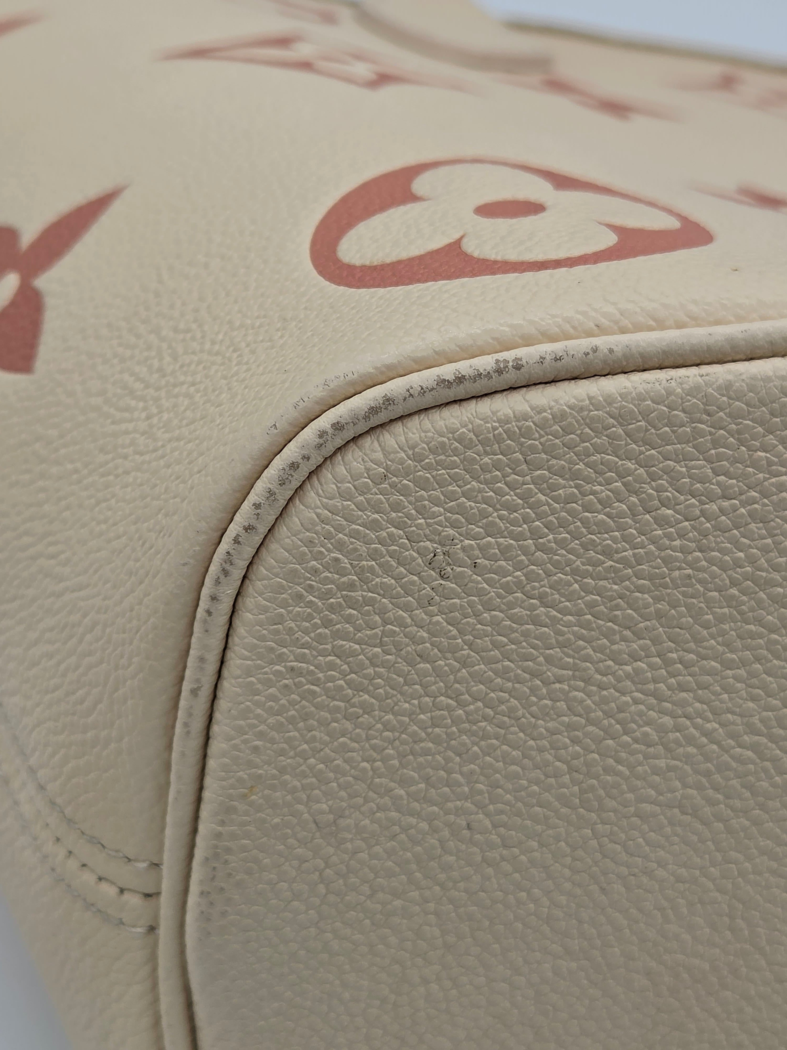 Close-up of beige leather seat with a logo on a vehicle interior.