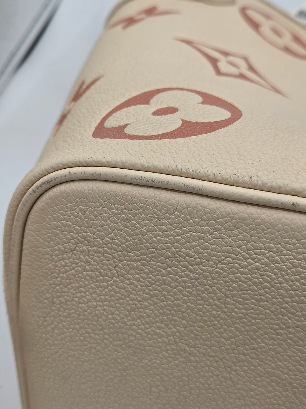 Close-up of a beige leather product with a red logo on a white background