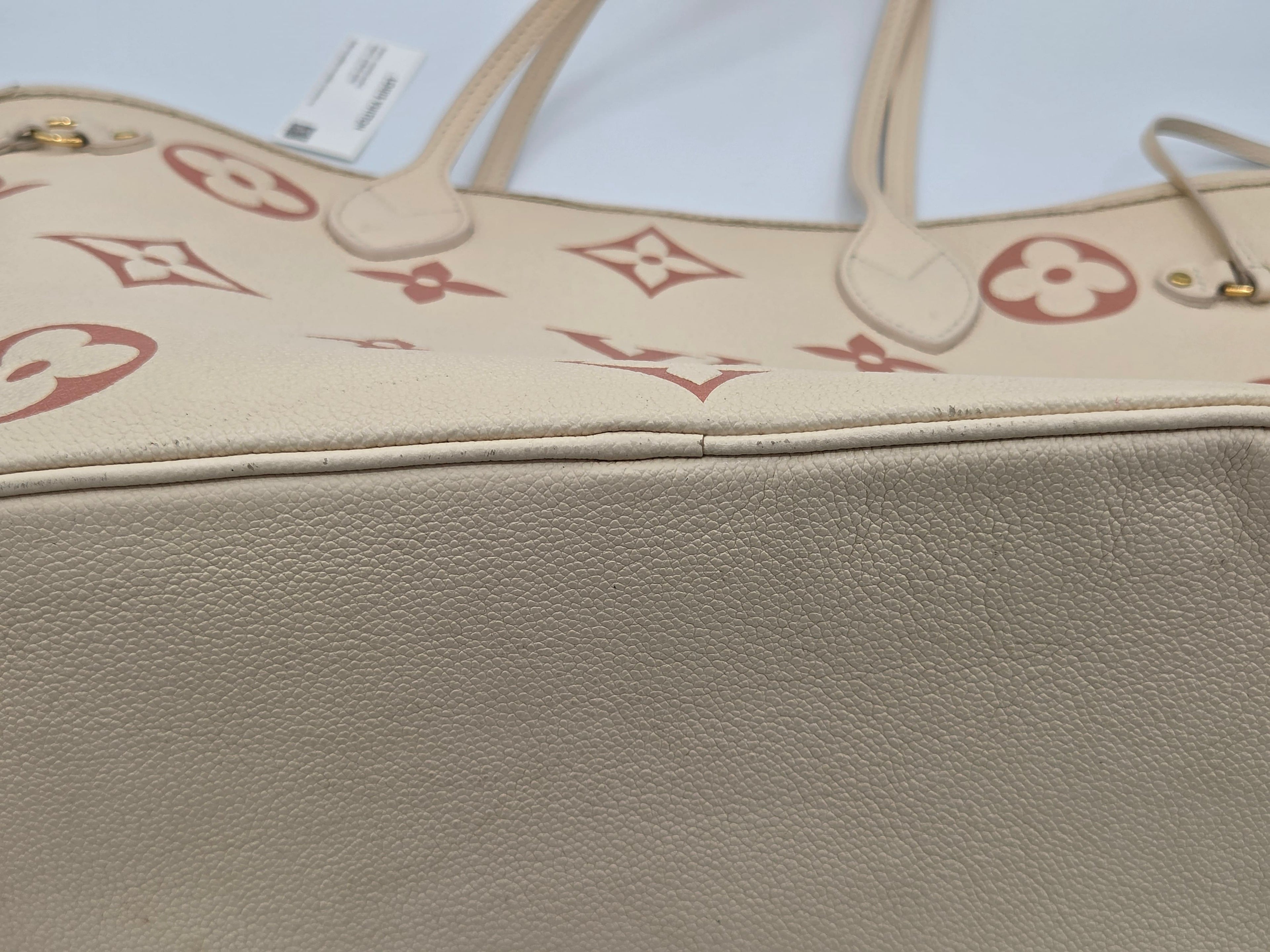 Beige handbag with red monogram pattern on a light gray background