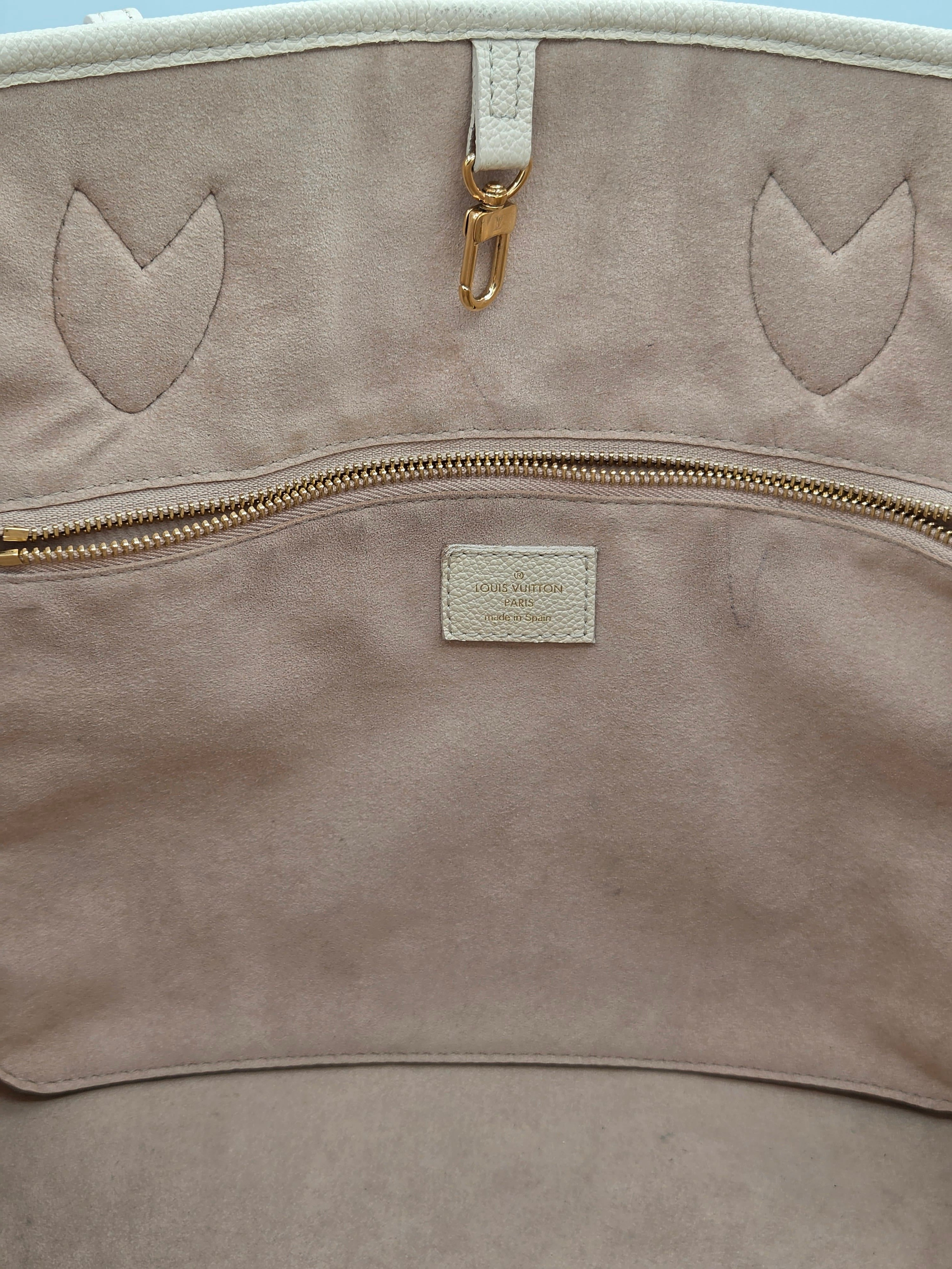 Close-up of a beige leather bag with gold zipper and decorative cutouts.