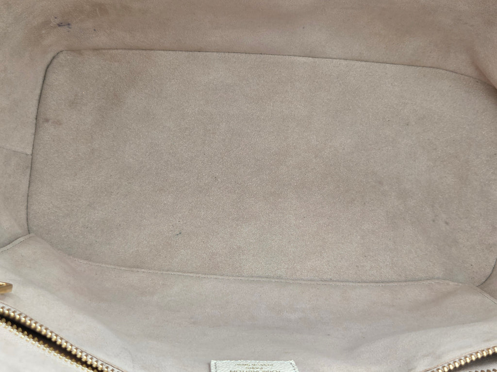 Close-up of a beige leather bag with visible wear and tear.
