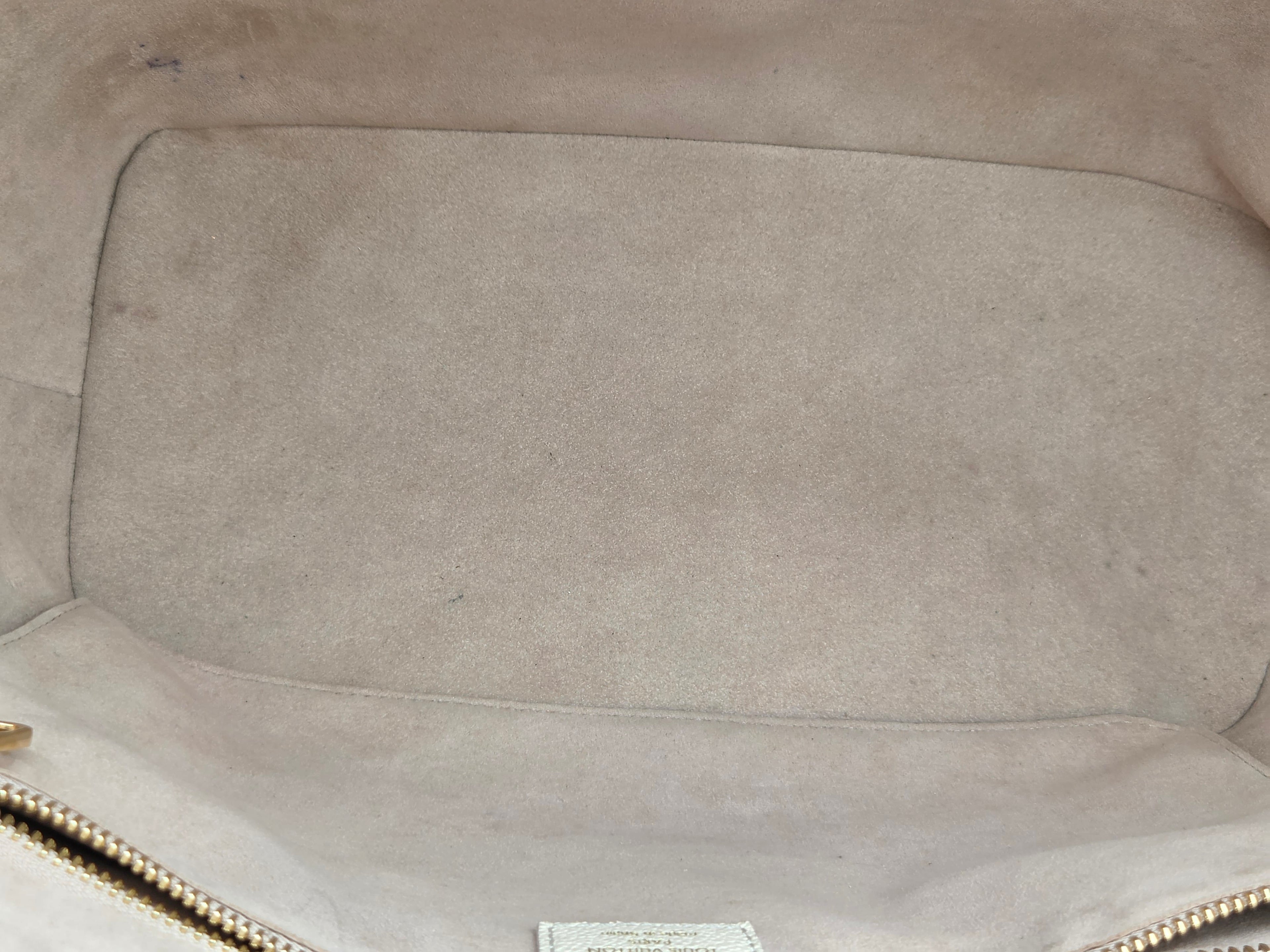 Close-up of a beige leather bag with visible wear and tear.