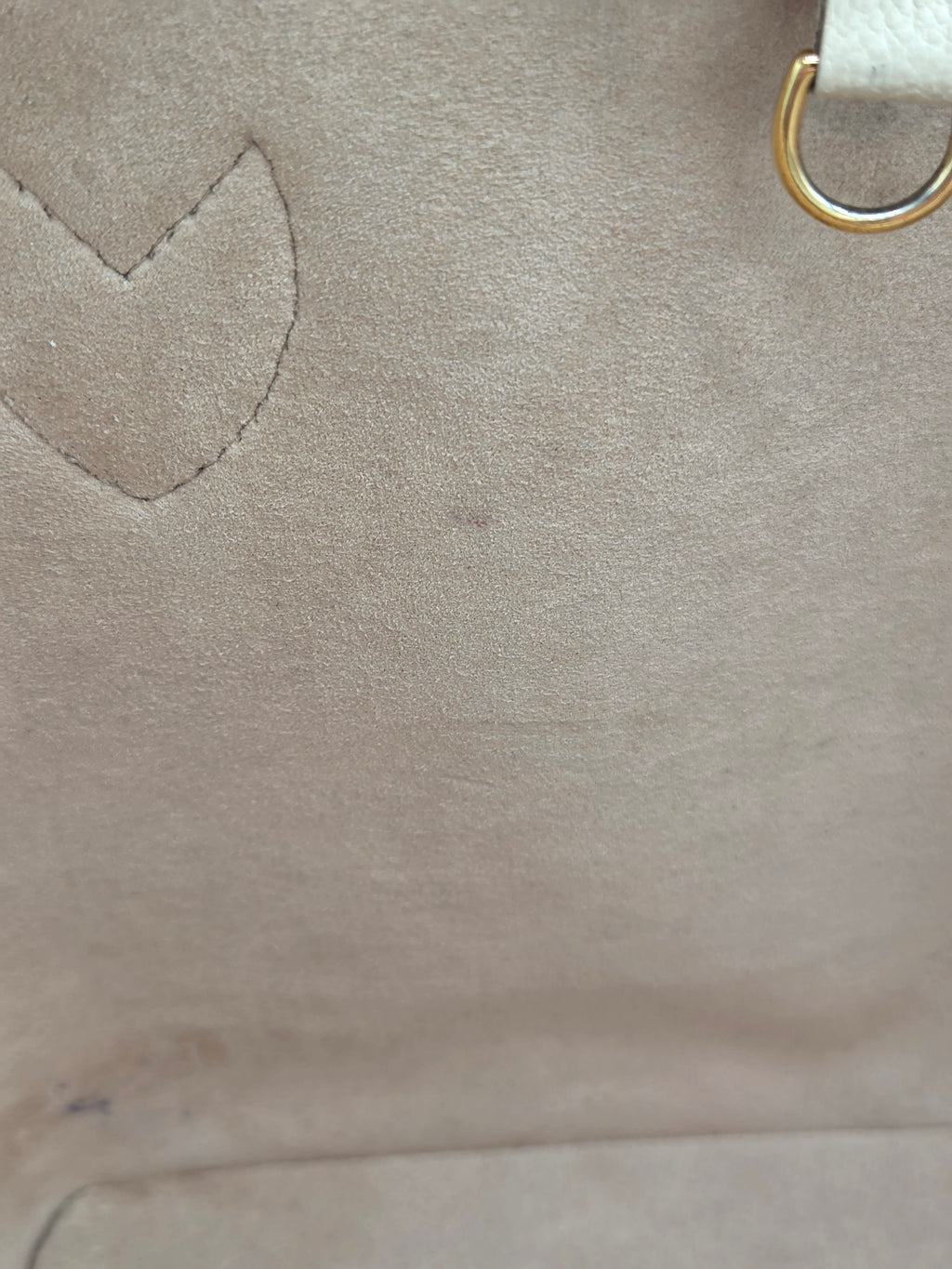 Close-up of a beige leather bag with a heart-shaped cutout and gold handle.