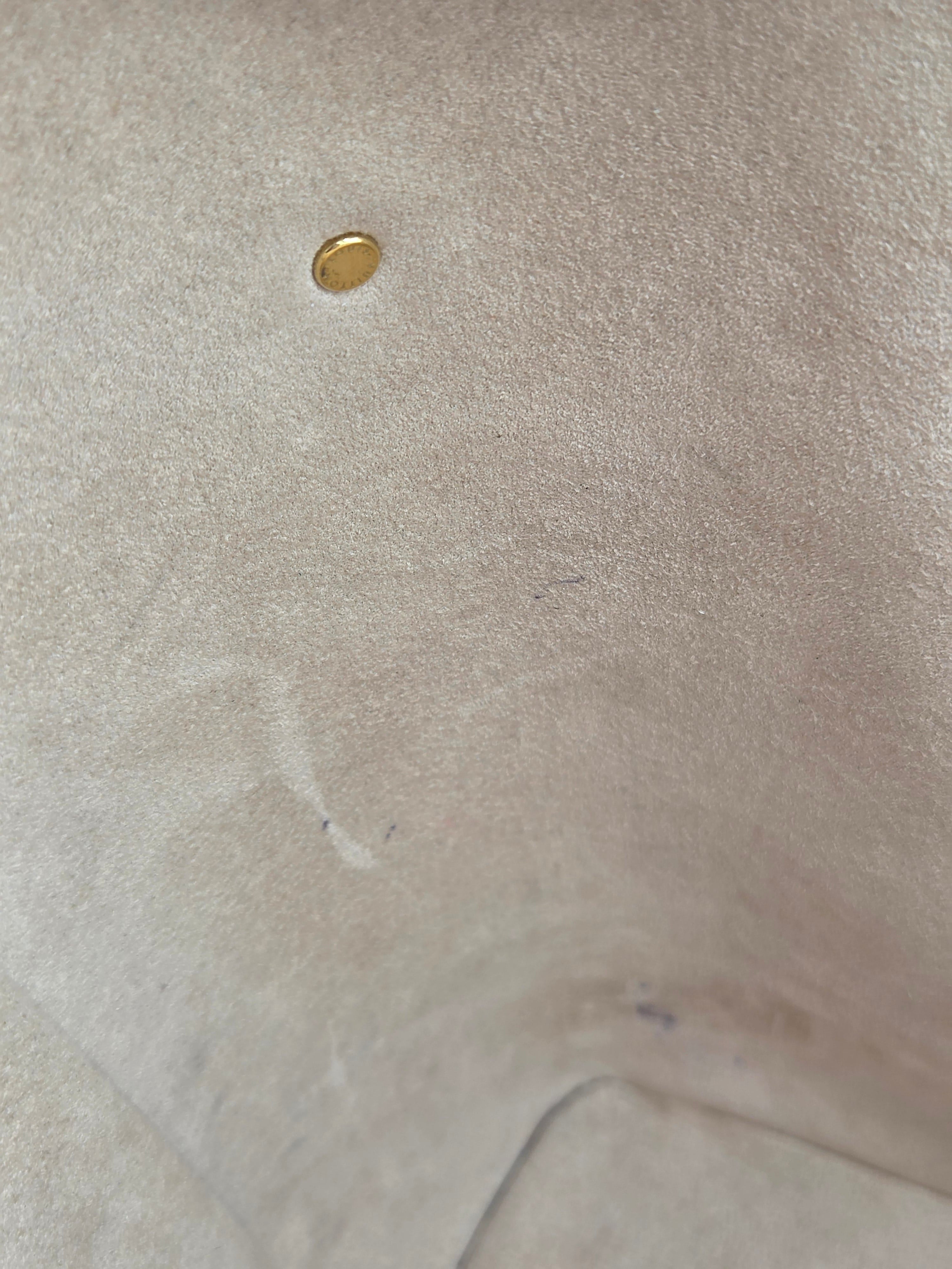 Close-up of a beige fabric surface with a gold button and visible thread.