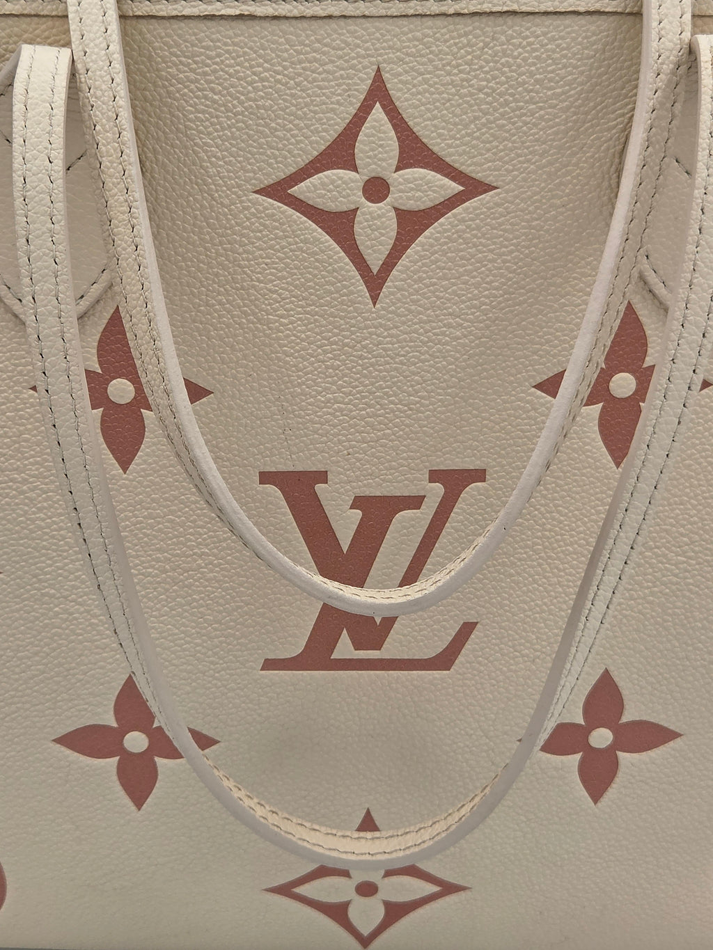 Close-up of a beige leather bag with red monogram pattern