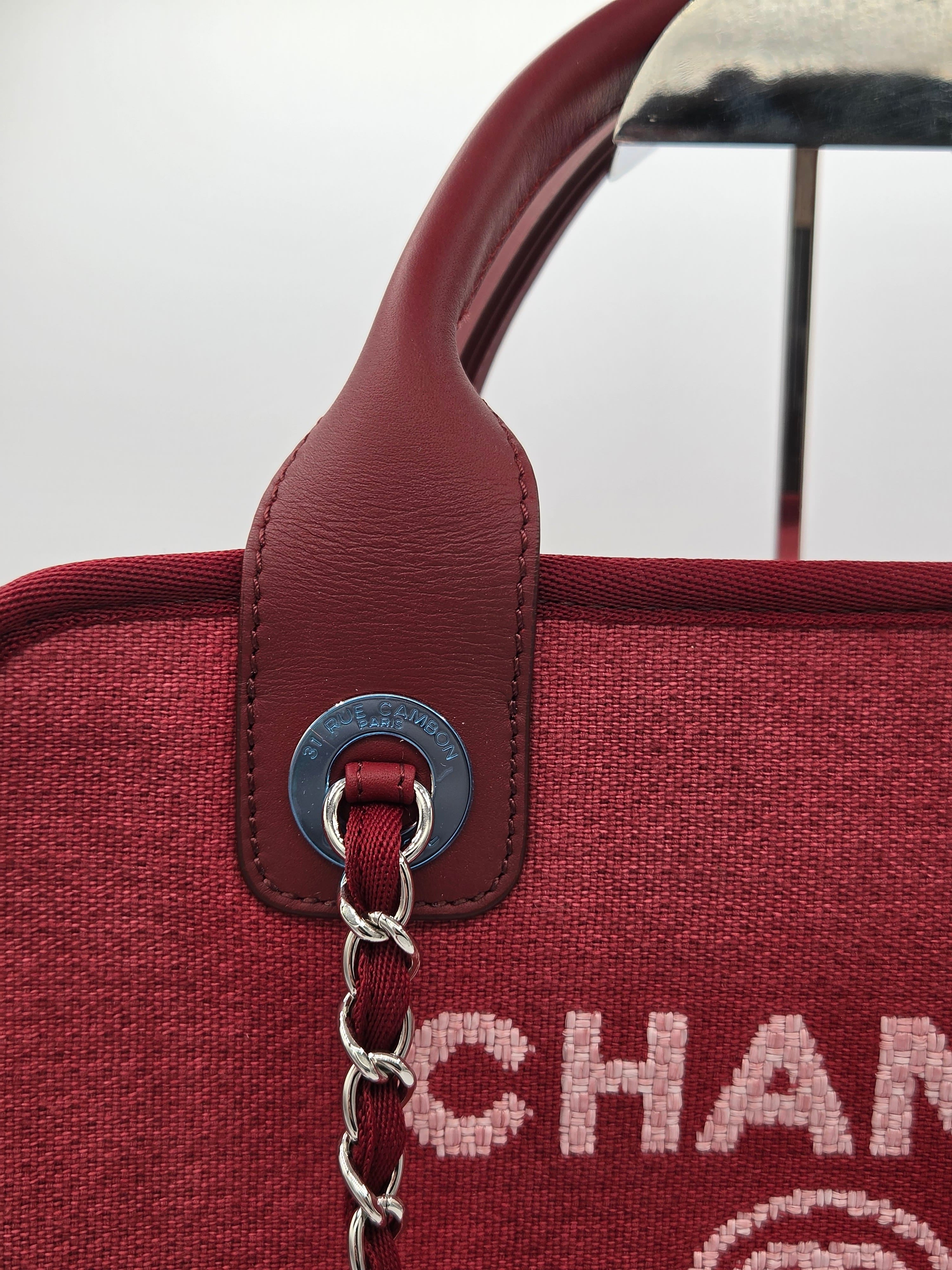 Close-up of a red handbag with a brown handle and visible brand name.
