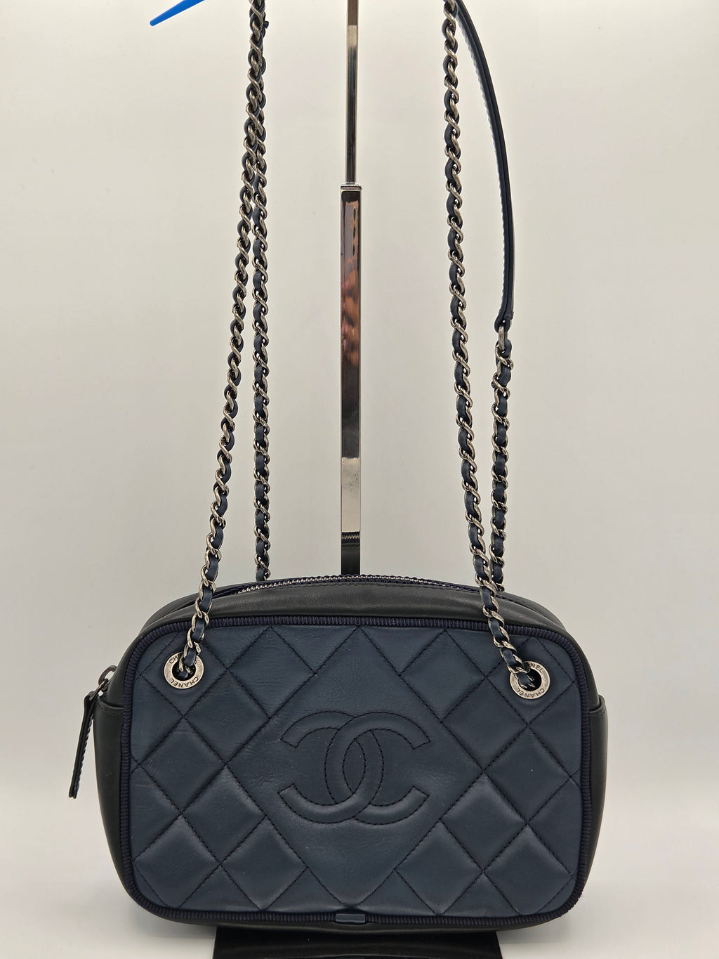 Black quilted handbag with chain strap on a light gray background