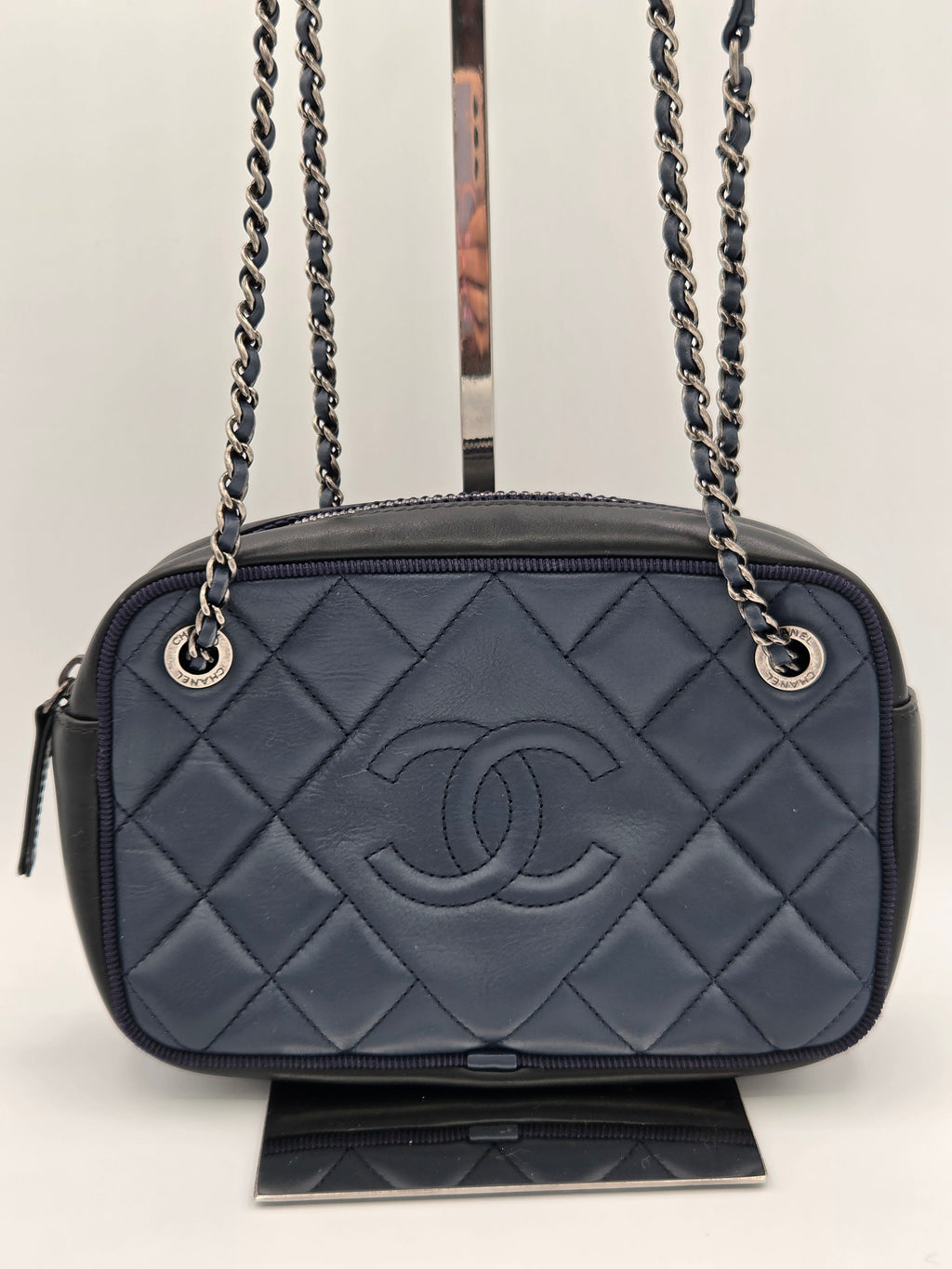 Gray quilted handbag with a chain strap on a light gray background