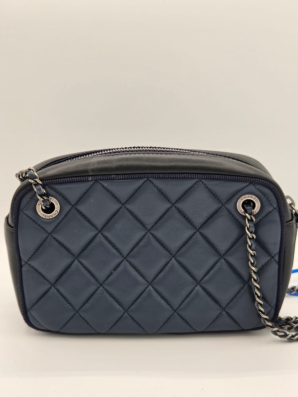 Quilted gray handbag with a chain strap on a light beige background