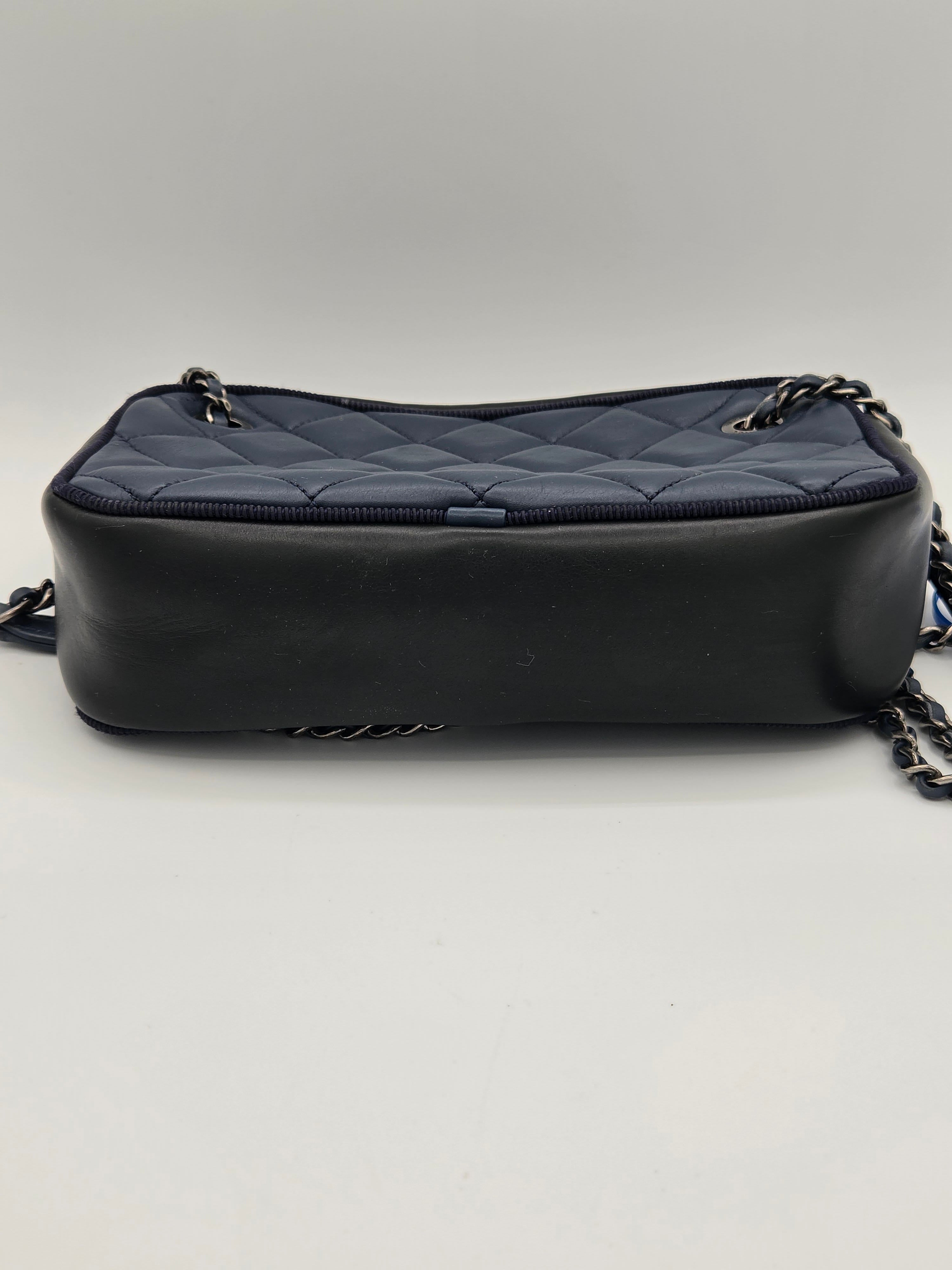 Black quilted handbag with a chain strap on a light gray background