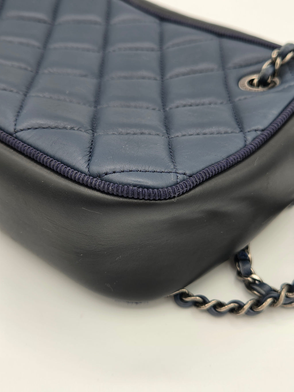 Close-up of a quilted handbag with a chain strap on a light background