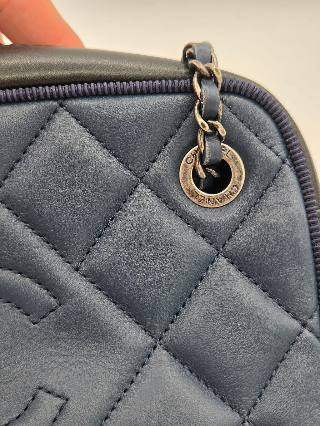 Close-up of a quilted blue handbag with a gold clasp.