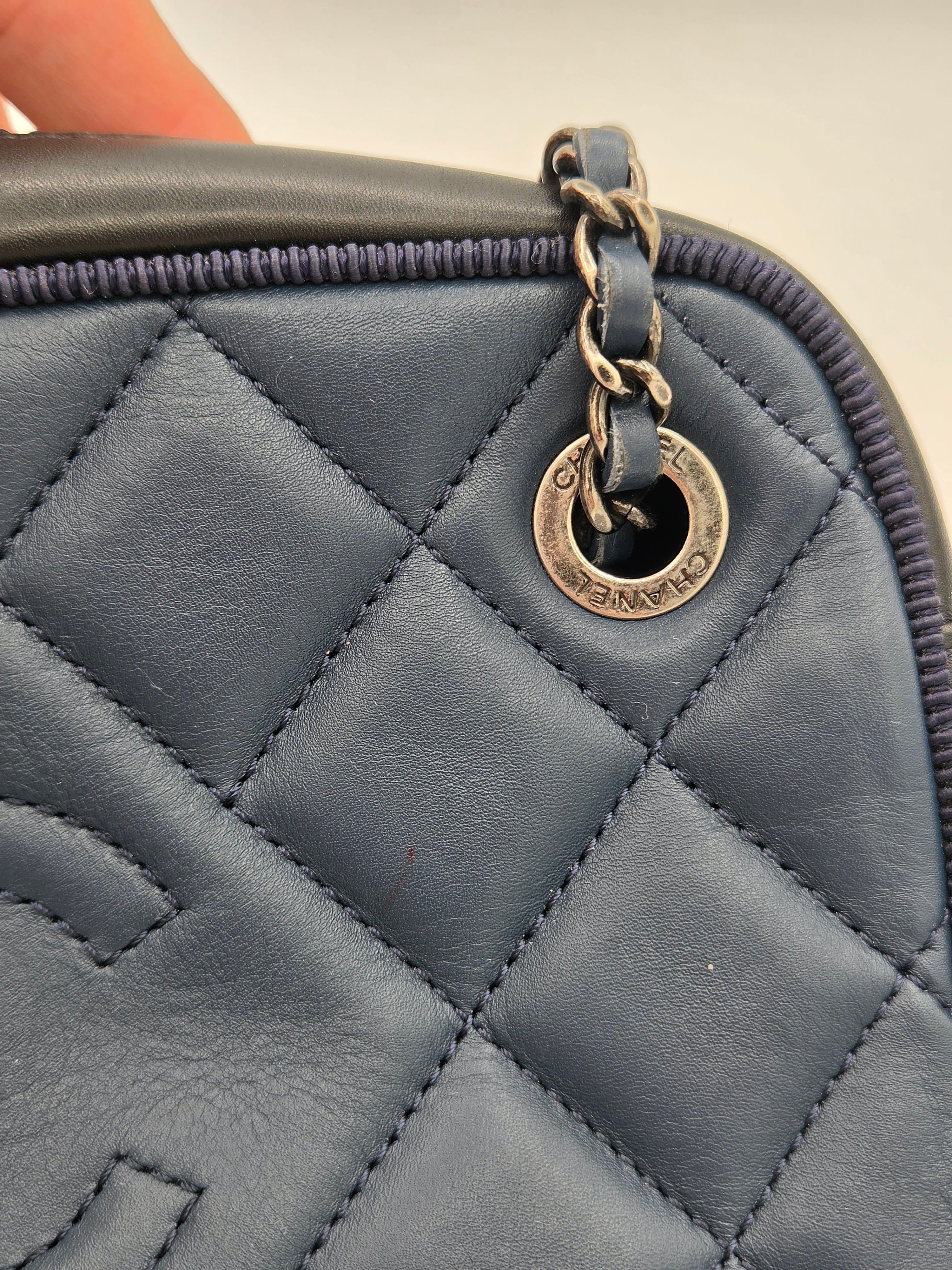 Close-up of a quilted blue handbag with a gold clasp.